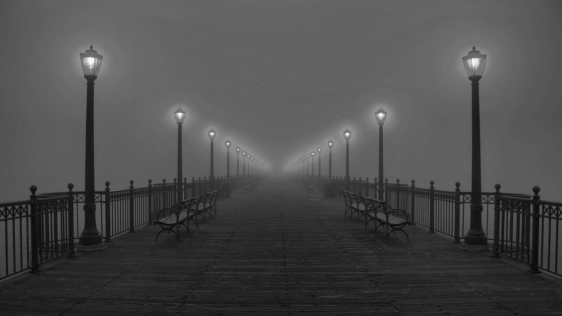 Black And White HD 桌布 壁紙 — 一個霧氣瀰漫的黑白碼頭延伸入霧中，兩側有發光的燈籠和空長椅。
