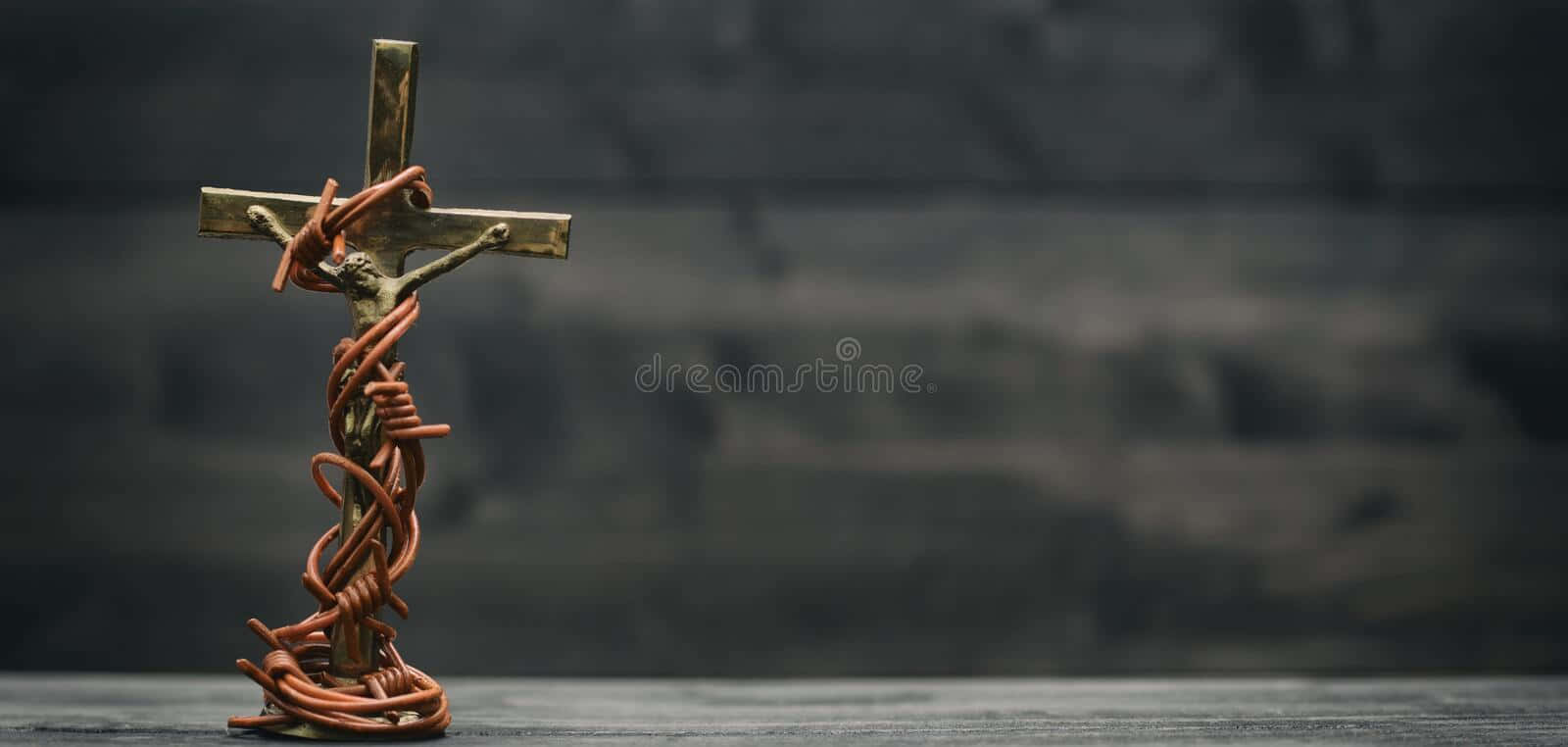 Religious Art 桌布 壁紙 — 一個青銅十字架纏繞著生鏽的鐵絲網，莊嚴地矗立在深色紋理木質背景前。