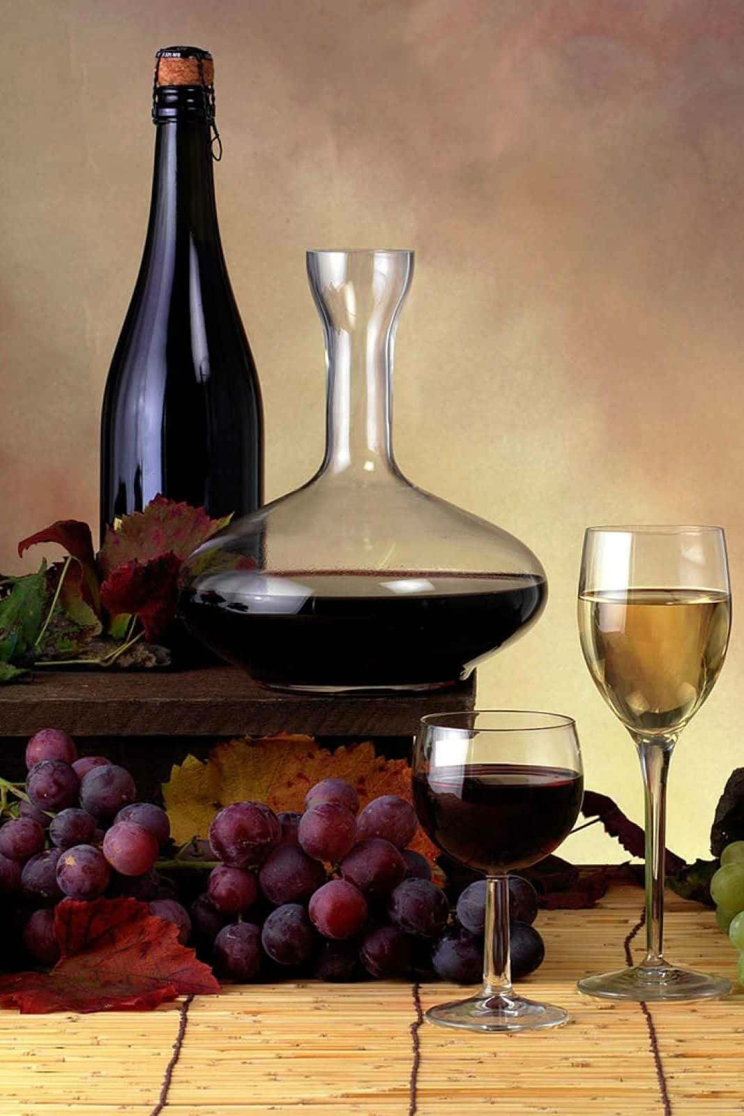 Black Wine 桌布 壁紙 — 一個靜物畫面，紅白酒杯、玻璃瓶和酒瓶被秋天的葡萄和樹葉圍繞，放在竹蓆上。