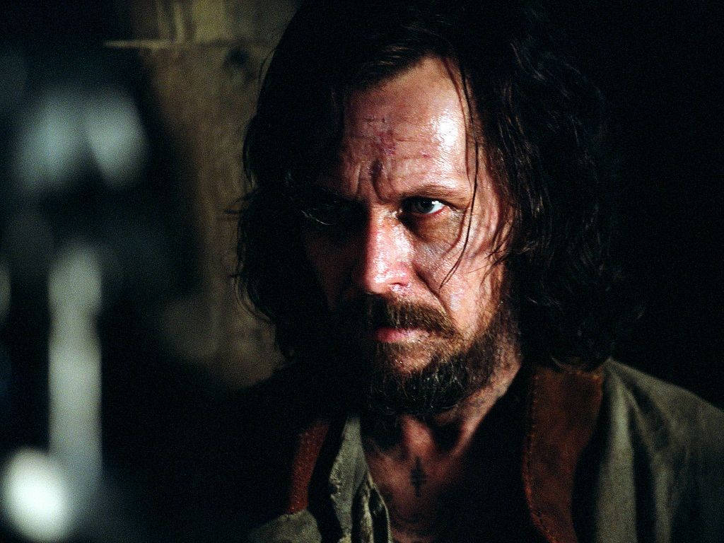 Sirius 桌布 壁紙 — 一個面容陰沉、長黑髮、留鬍鬚的男人，在昏暗骯髒的環境中凝視。