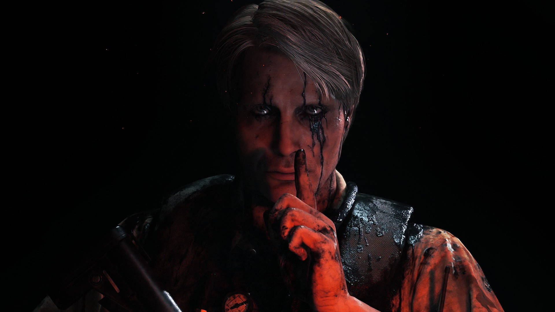 Mads Mikkelsen 桌布 壁紙 — 一個面容陰沉的男人，臉上帶有血痕，衣服沾滿污漬，在黑色背景前豎起一根手指示意安靜。