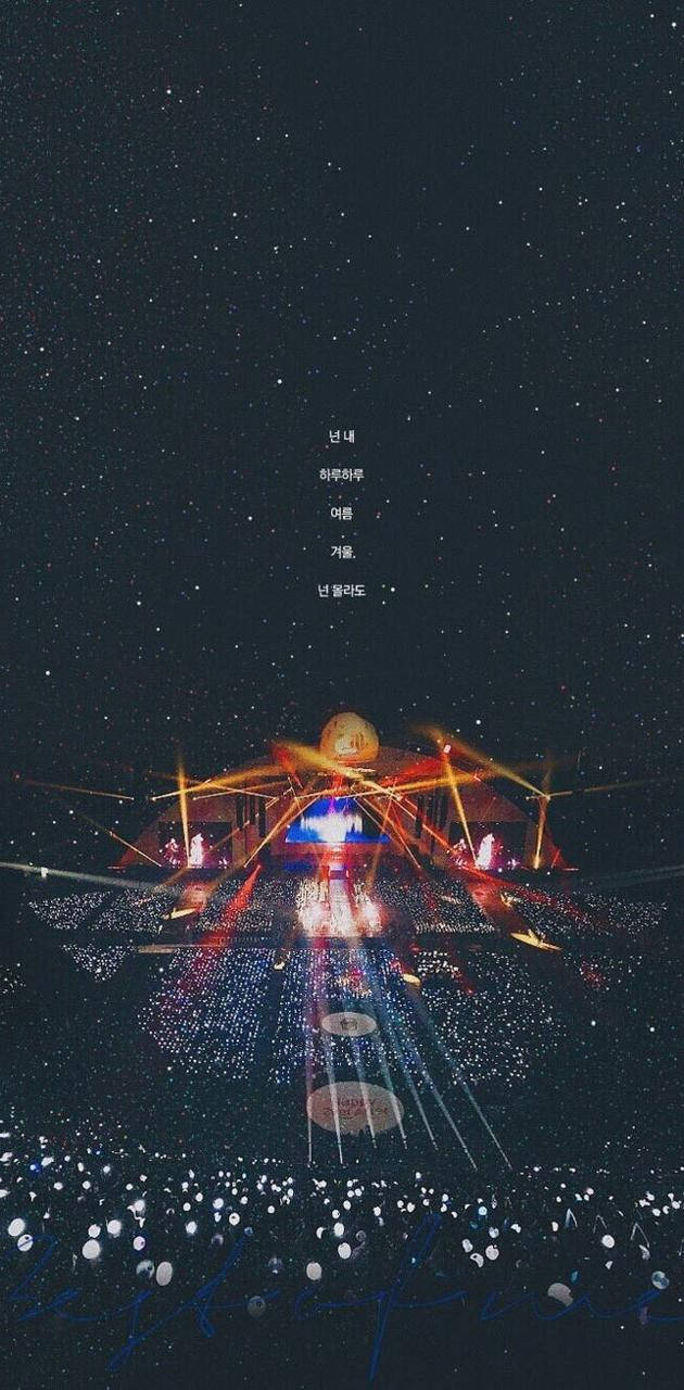 一個燈火通明的音樂會舞台，在繁星點點的夜空下，觀眾燈光閃爍。 — BTS ARMY GIF 壁紙