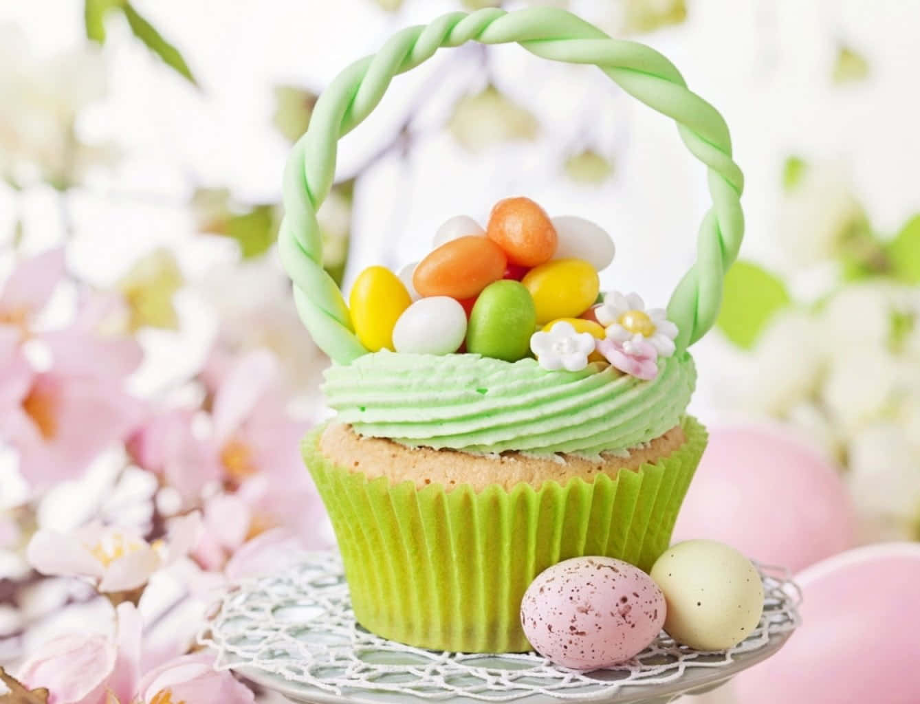 Spring Desserts 桌布 壁紙 — 一個頂部有綠色糖霜的杯子蛋糕，以及一個裝滿彩色蛋和花朵的糖果籃。