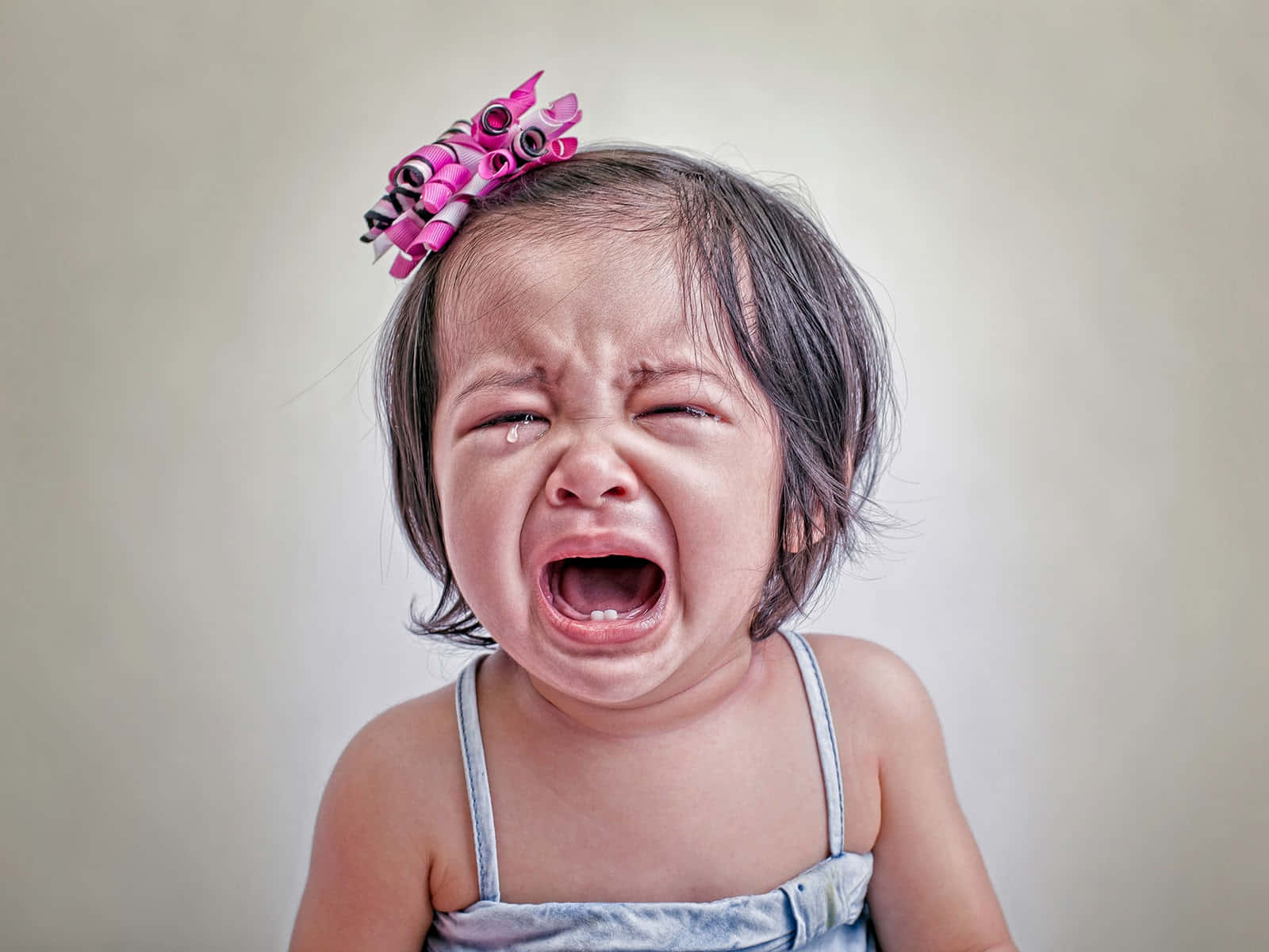cry 桌布 壁紙 — 一個頭上戴著粉紅色髮捲的幼兒大聲哭泣，眼睛緊閉，淚水順著臉頰流下。