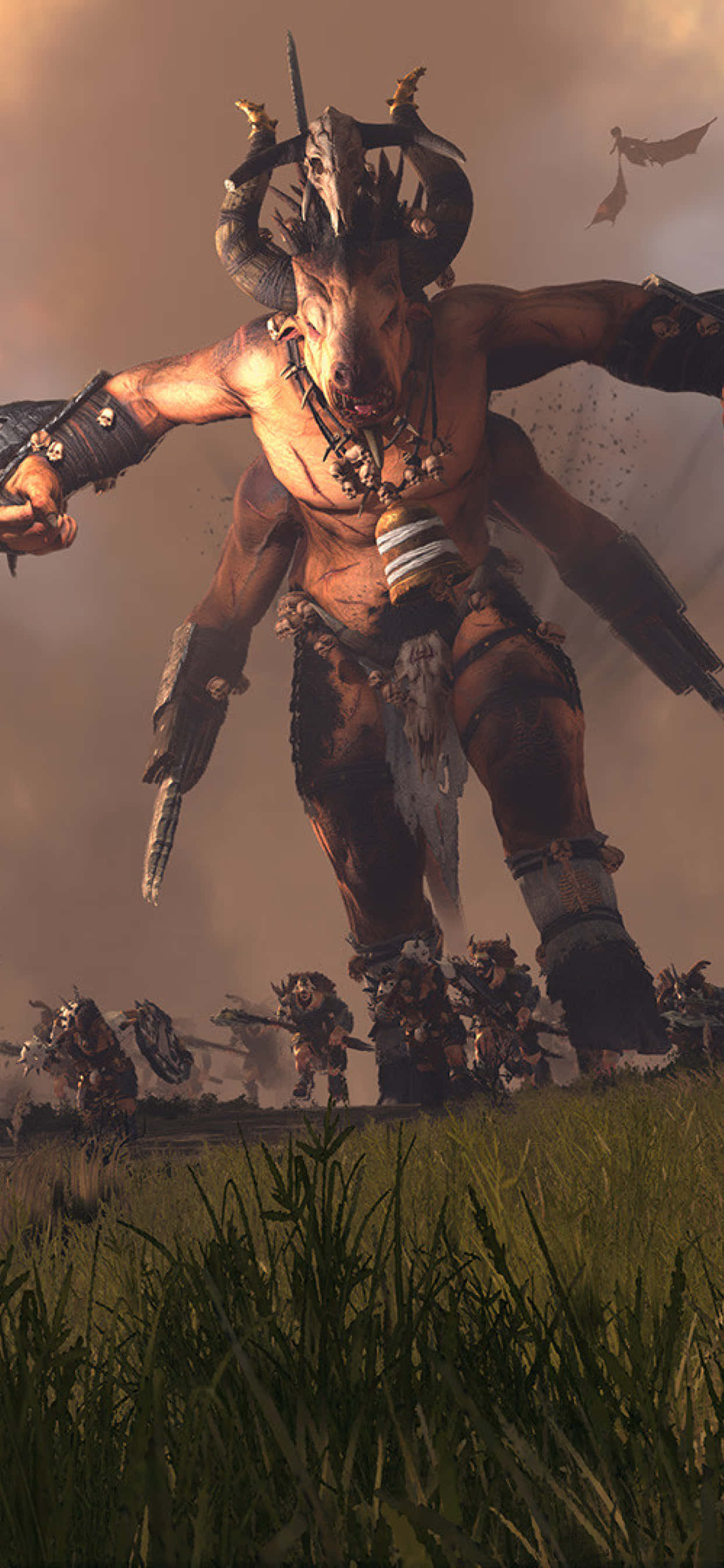 iPhone X Total War Warhammer 桌布 壁紙 — 一個頭戴骷髏頭飾、身穿盔甲、高大有角的牛頭人戰士，威嚇地站在草地上一個由較小戰士組成的戰場上。