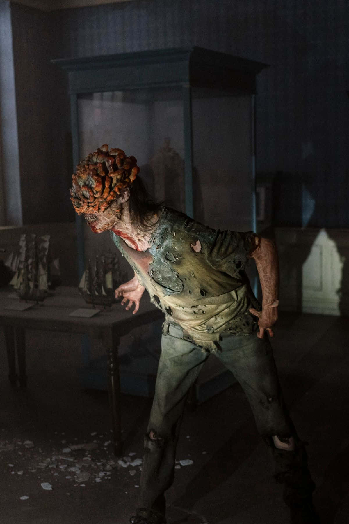Zombie 桌布 壁紙 — 一個頭部腐爛、衣服破爛的怪異殭屍在昏暗多塵的房間裡向前猛撲。