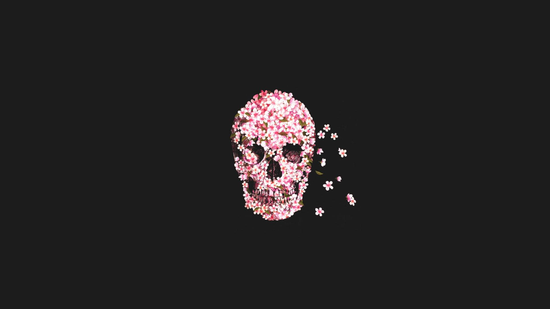Pink Roses 桌布 壁紙 — 一個頭骨裝飾著精緻的粉紅色櫻花，漂浮在 stark 黑色背景上，花瓣飄散。
