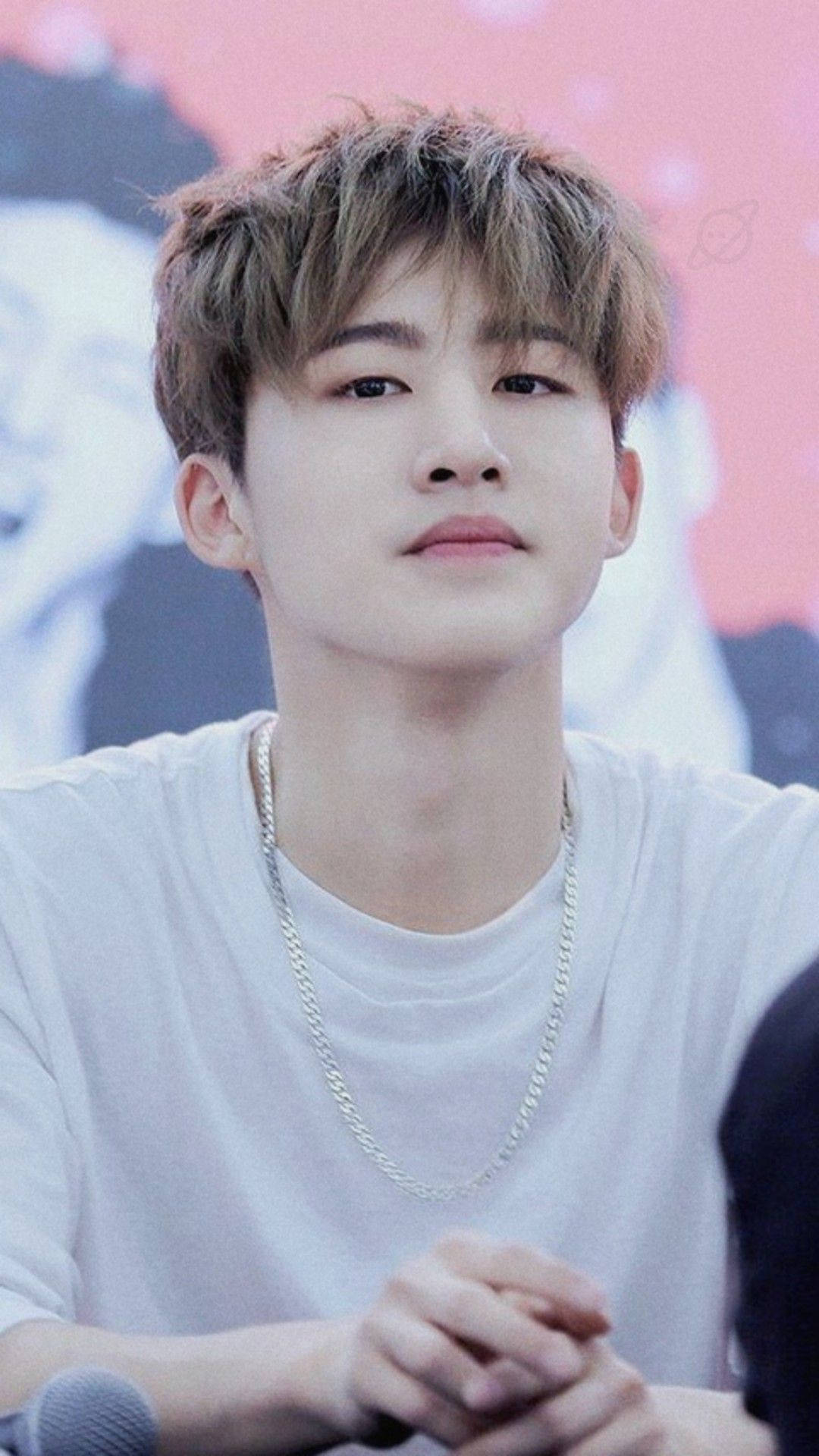 Ikon 桌布 壁紙 — 一個頭髮凌亂、戴著銀鏈的年輕男子坐在麥克風前沉思。