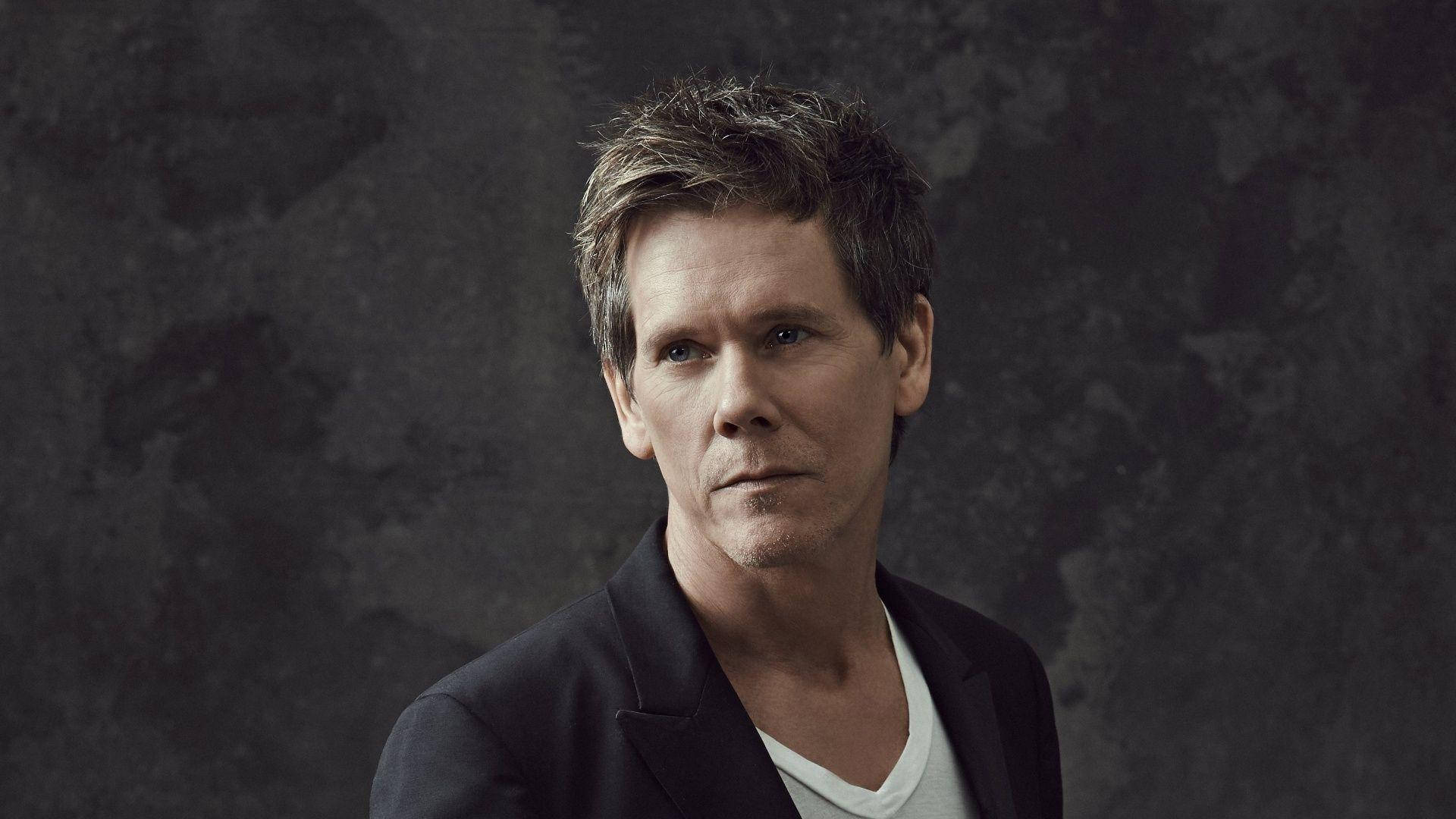 Celebrity 桌布 壁紙 — 一個頭髮凌亂、眼神銳利的男人，在紋理深灰色背景前直視鏡頭。