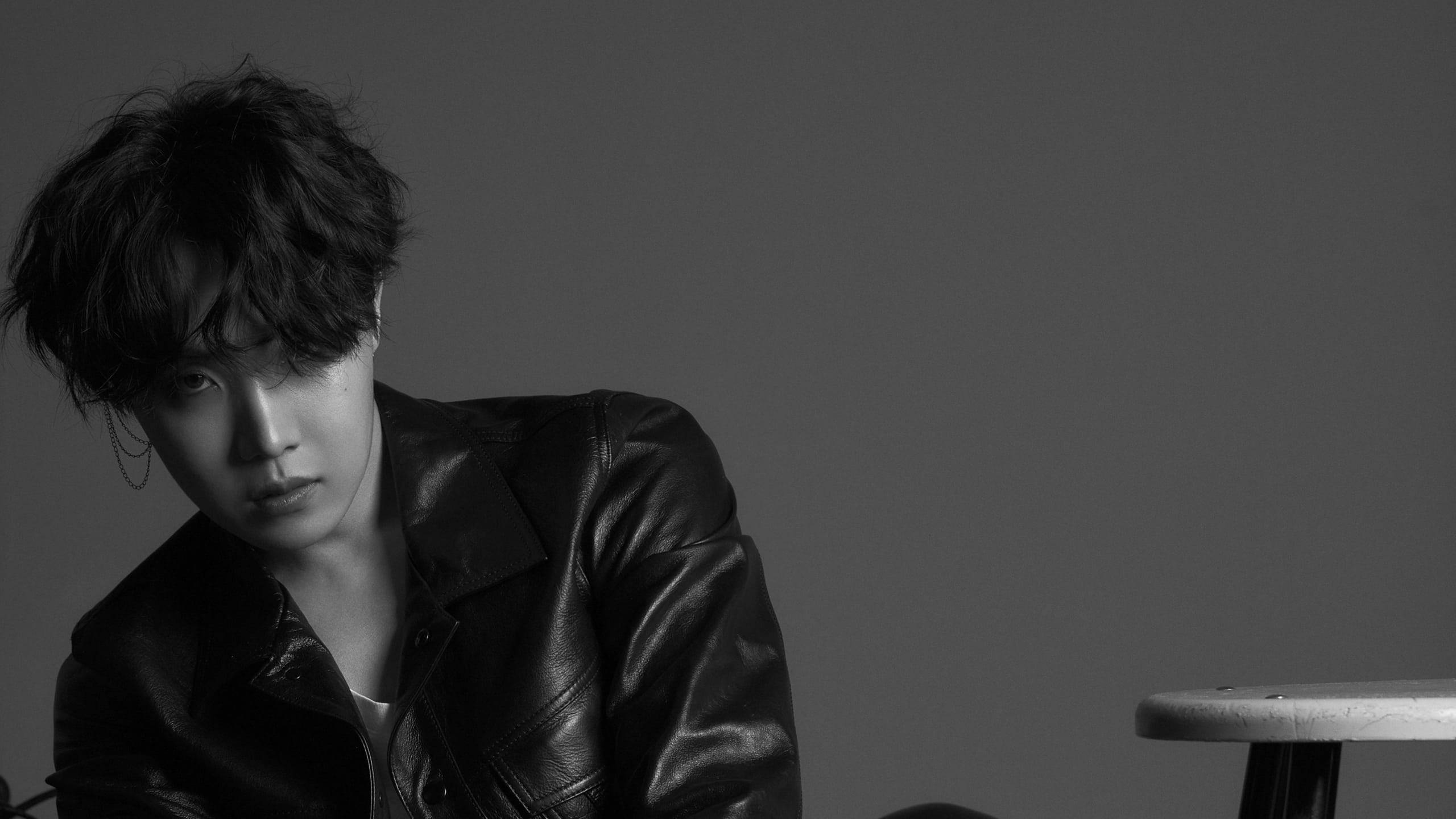 Bts Black Aesthetic 桌布 壁紙 — 一個頭髮凌亂的年輕男子穿著皮夾克，在純灰色背景下專注地凝視。