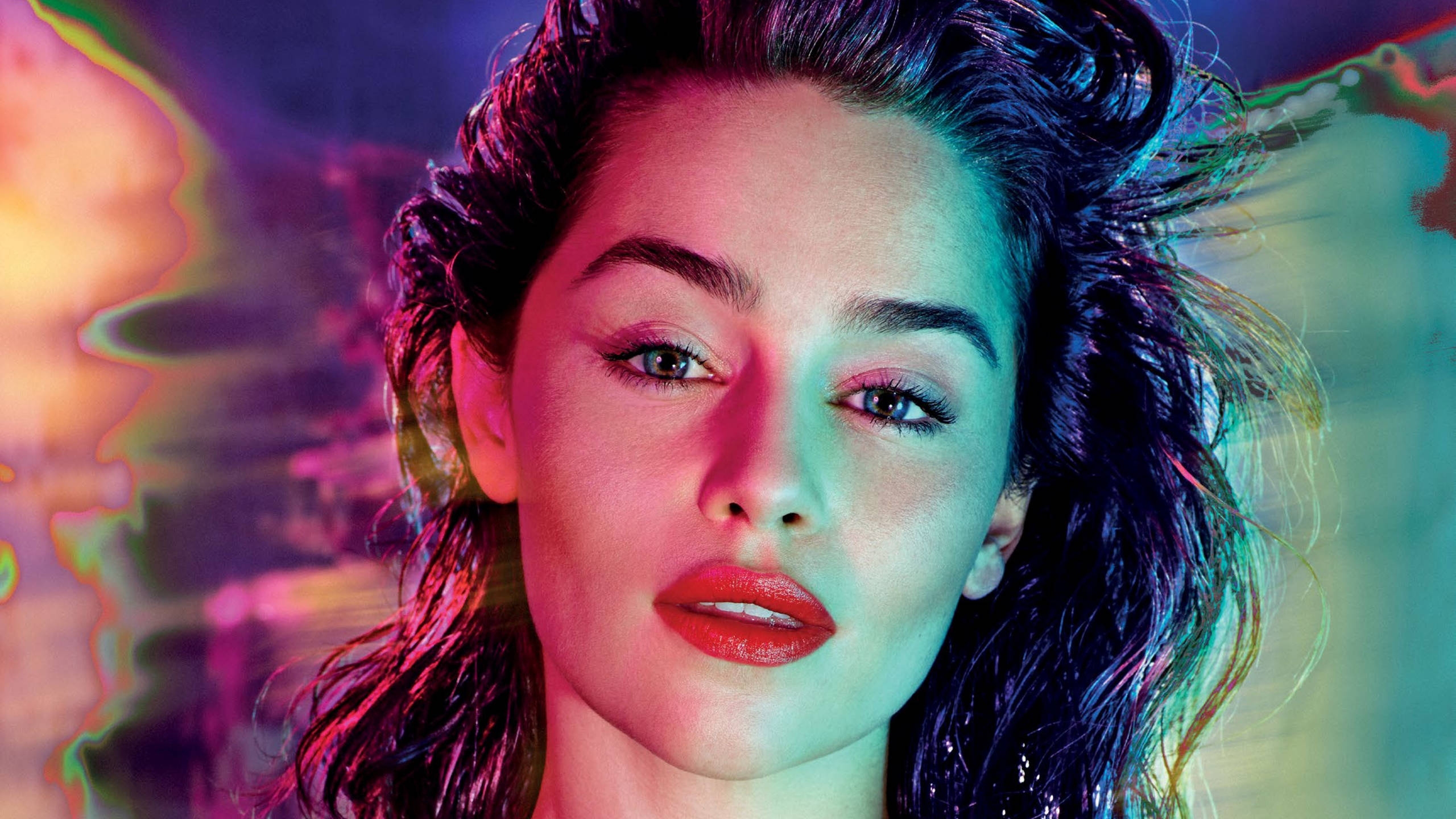 Emilia 桌布 壁紙 — 一個頭髮濕透、嘴唇鮮紅的女人，在充滿活力的霓虹色抽象背景下凝視著。