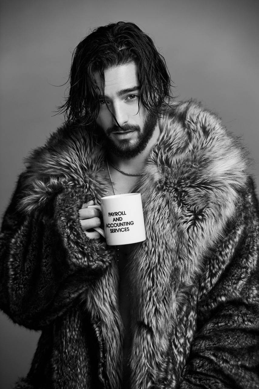 Maluma 桌布 壁紙 — 一個頭髮濕透、留鬍子的男人穿著皮草大衣，拿著一個標有薪資和會計服務的杯子，在黑白攝影棚肖像中營造出陰鬱的氛圍。