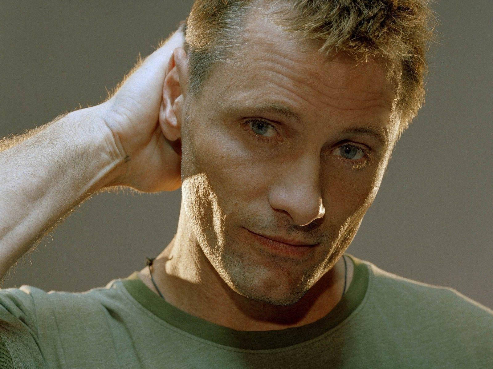 actor 桌布 壁紙 — 一個頭髮蓬亂、擁有強烈藍眼的男人，將手放在頭上，直視鏡頭。