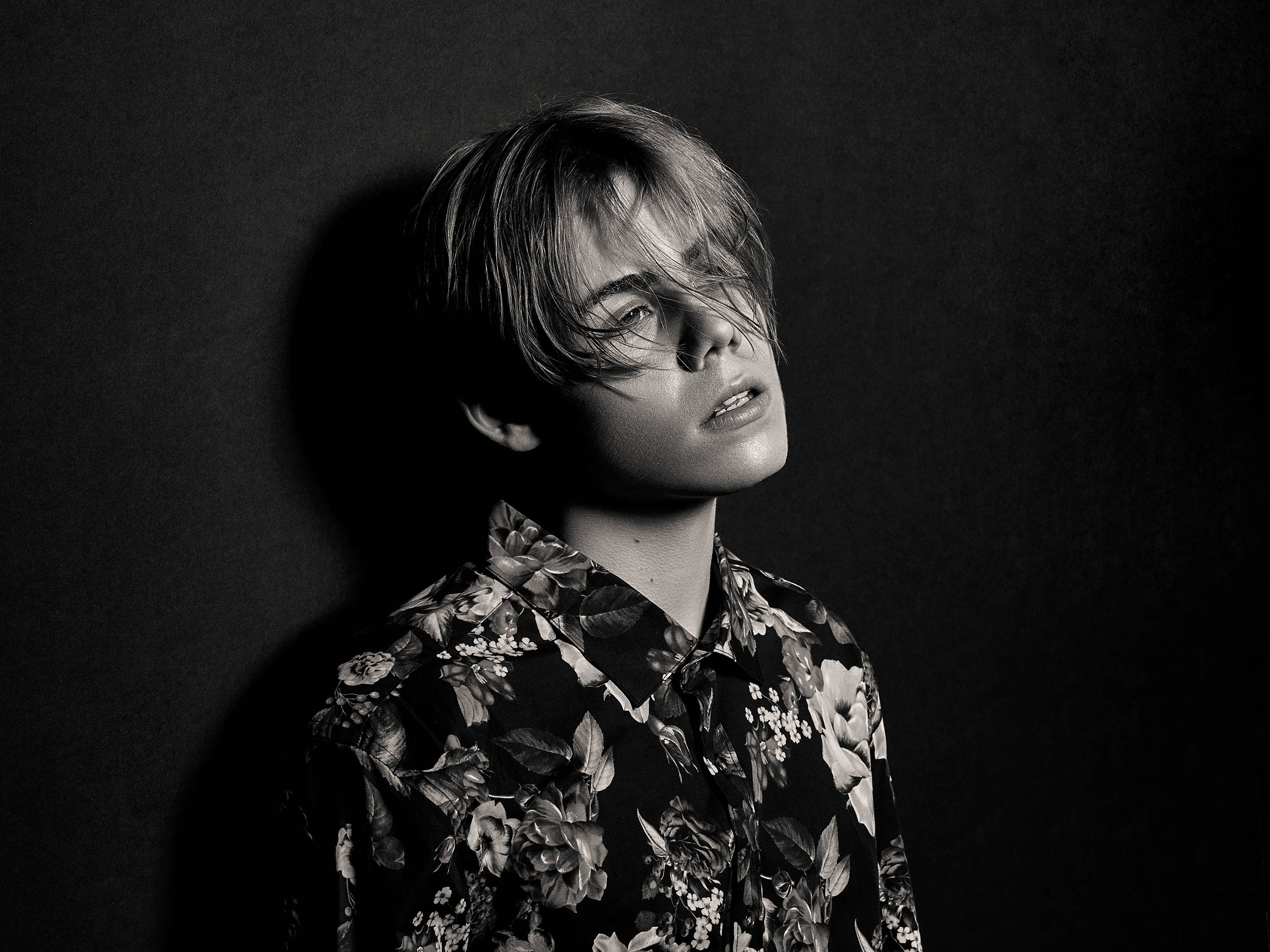 kid 桌布 壁紙 — 一個頭髮蓬亂的年輕人在黑暗背景下向上望的戲劇性黑白肖像。