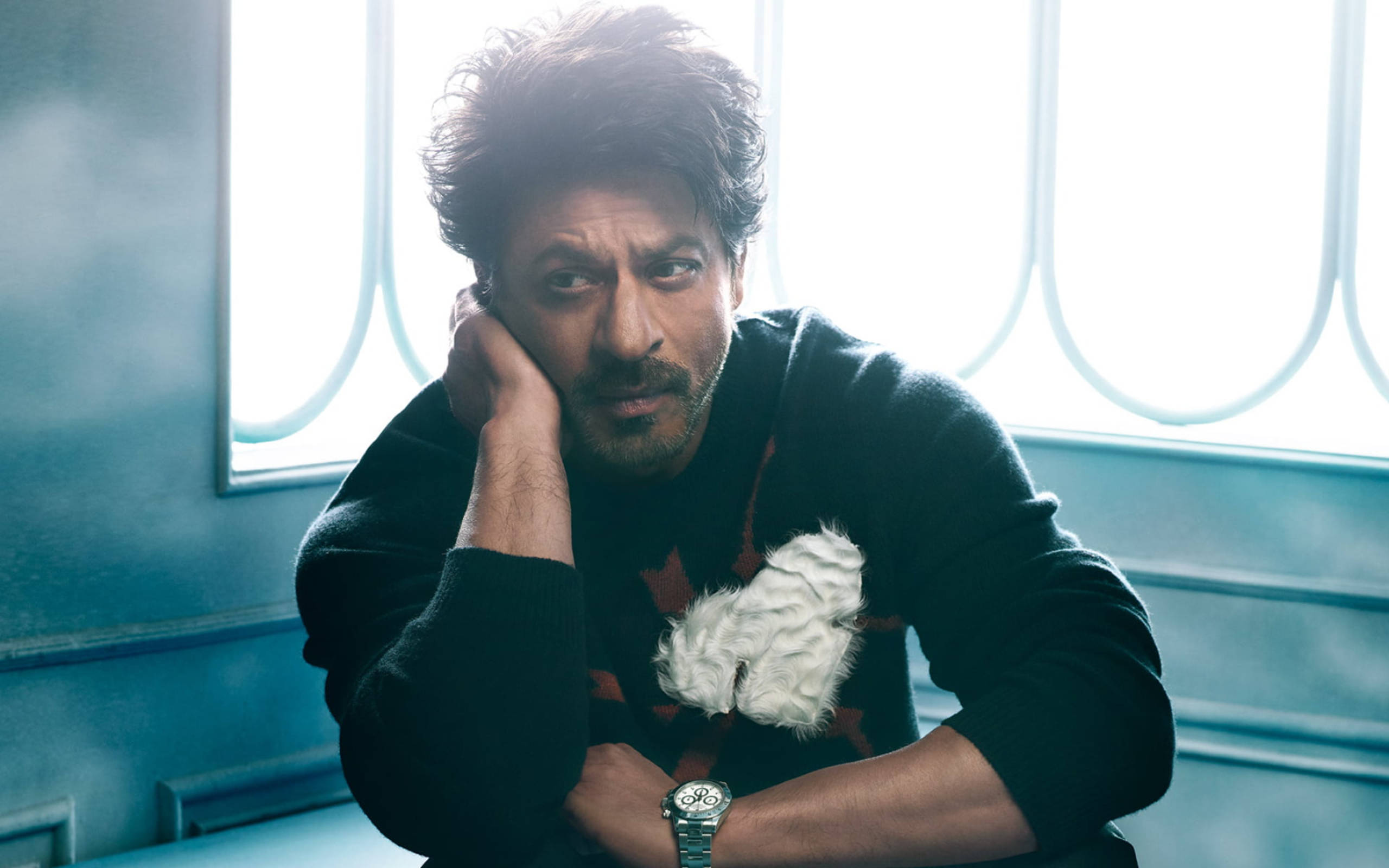 Shah Rukh Khan 桌布 壁紙 — 一個頭髮蓬鬆的男人，在有弧形窗格的明亮窗邊，將頭靠在手上。