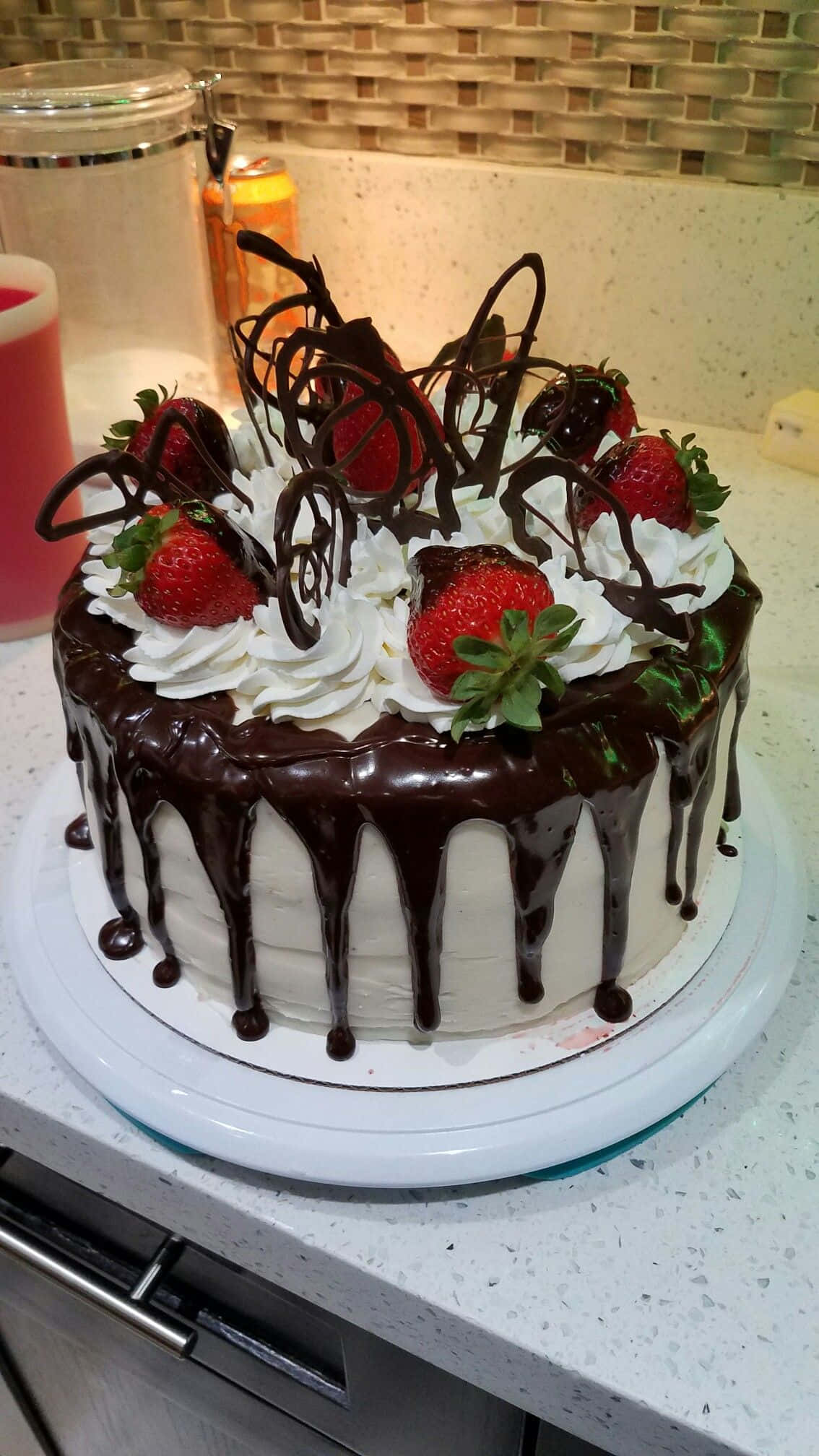 Black Forest Cake 桌布 壁紙 — 一個頹廢的巧克力滴落蛋糕，上面鋪滿新鮮草莓和鮮奶油，放在廚房檯面上。