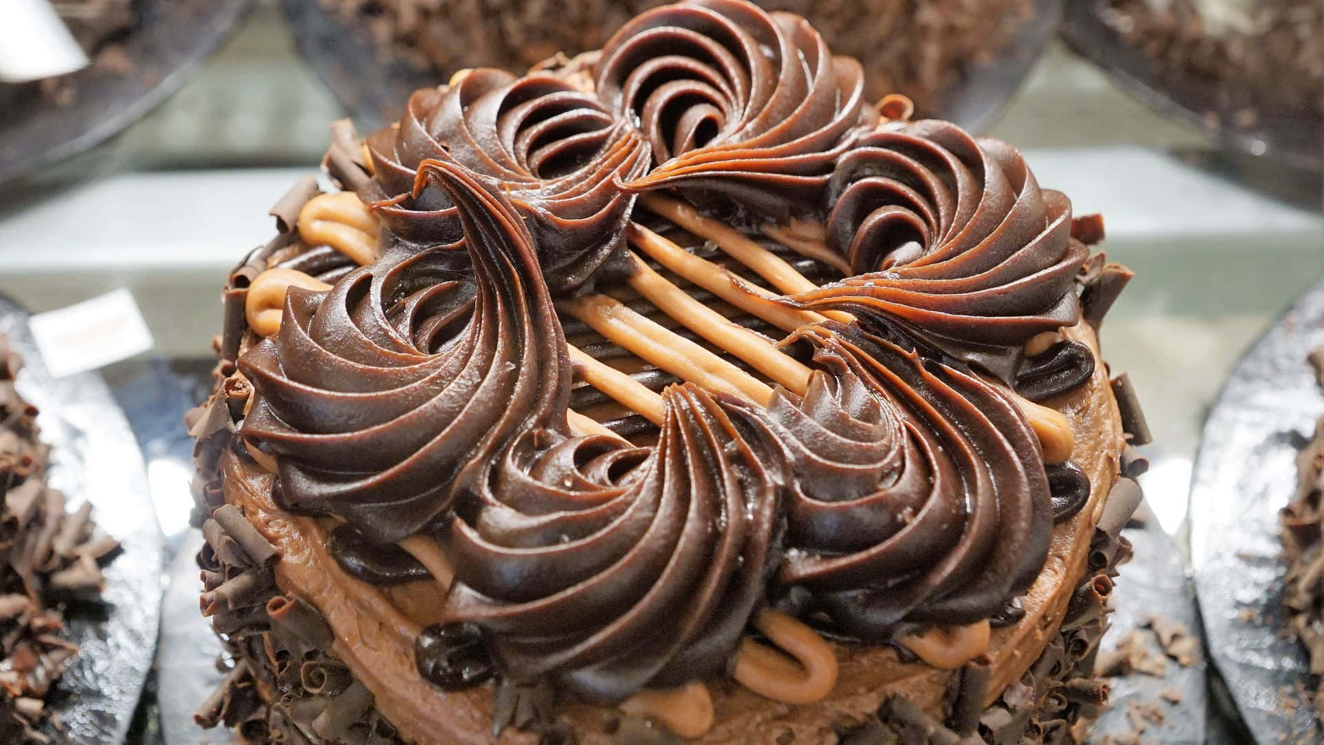 Chocolate 桌布 壁紙 — 一個頹廢的巧克力蛋糕，上面有光澤的深色巧克力糖霜漩渦和焦糖淋醬。