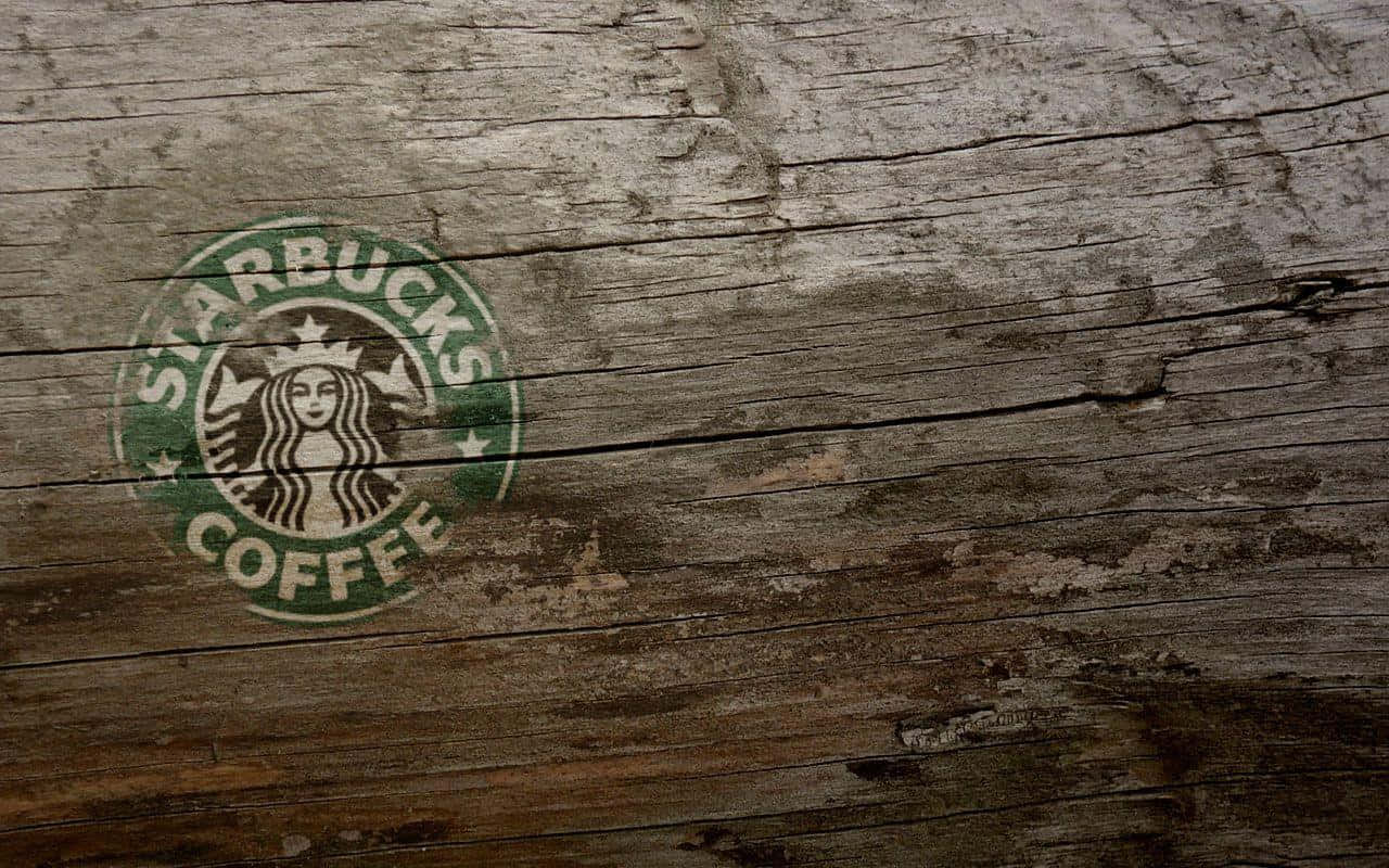 星巴克 桌布 壁紙 — 一個風化的Starbucks標誌，塗在粗糙紋理的木板上，可見木紋和裂縫。