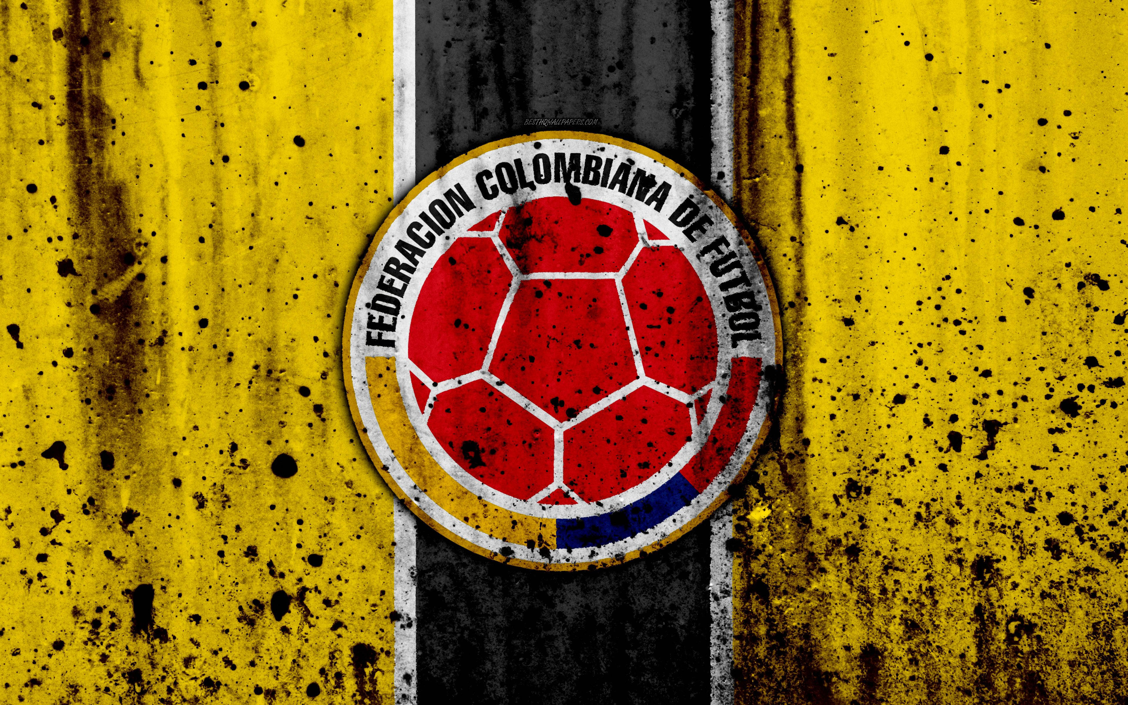 Colombia 桌布 壁紙 — 一個風化的哥倫比亞足球聯合會標誌，居中在粗糙的黃黑條紋背景上，帶有飛濺效果。