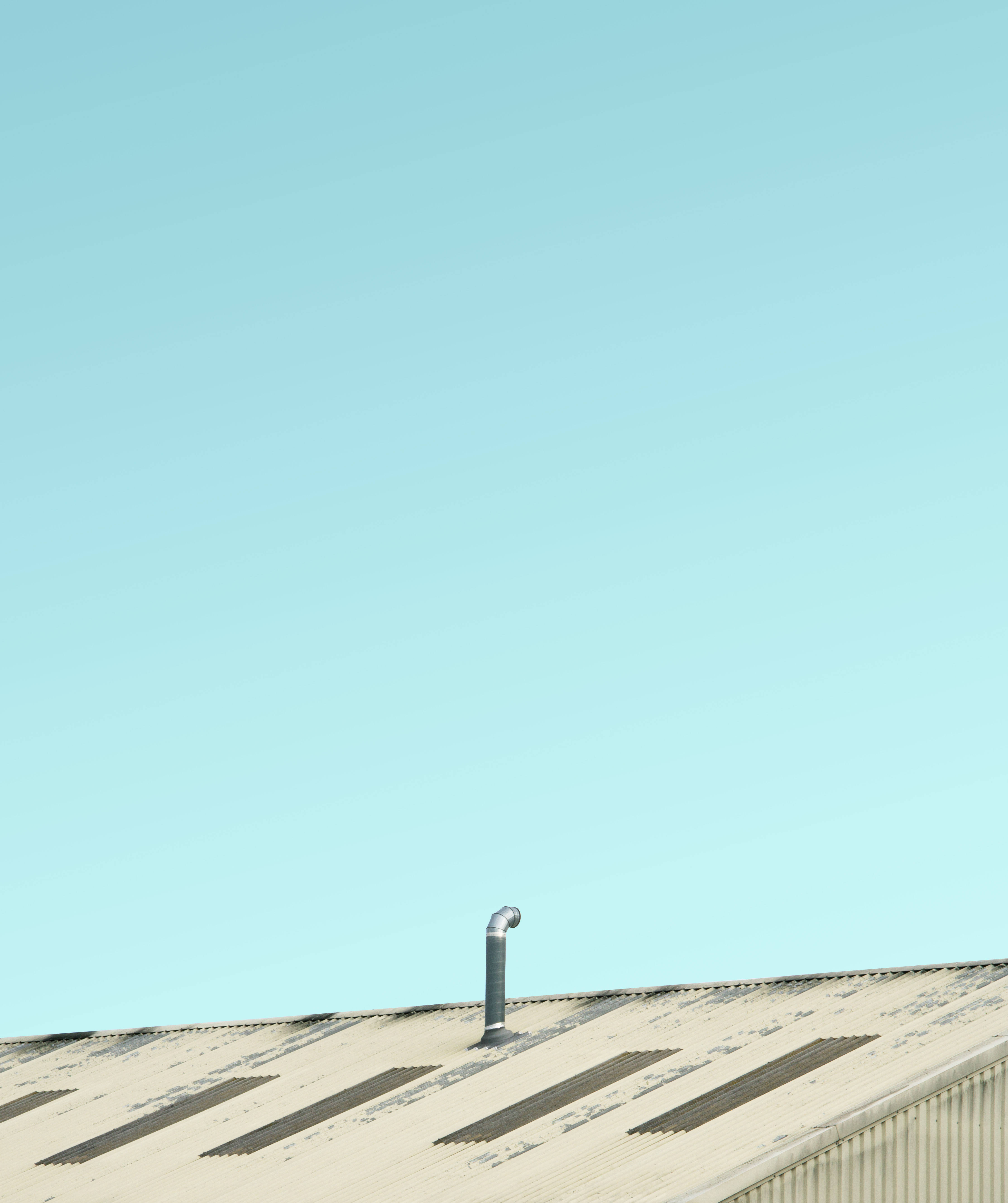 Blue Sky 桌布 壁紙 — 一個風化的波紋金屬屋頂，帶有銀色通風管，襯著廣闊清澈的青色天空。