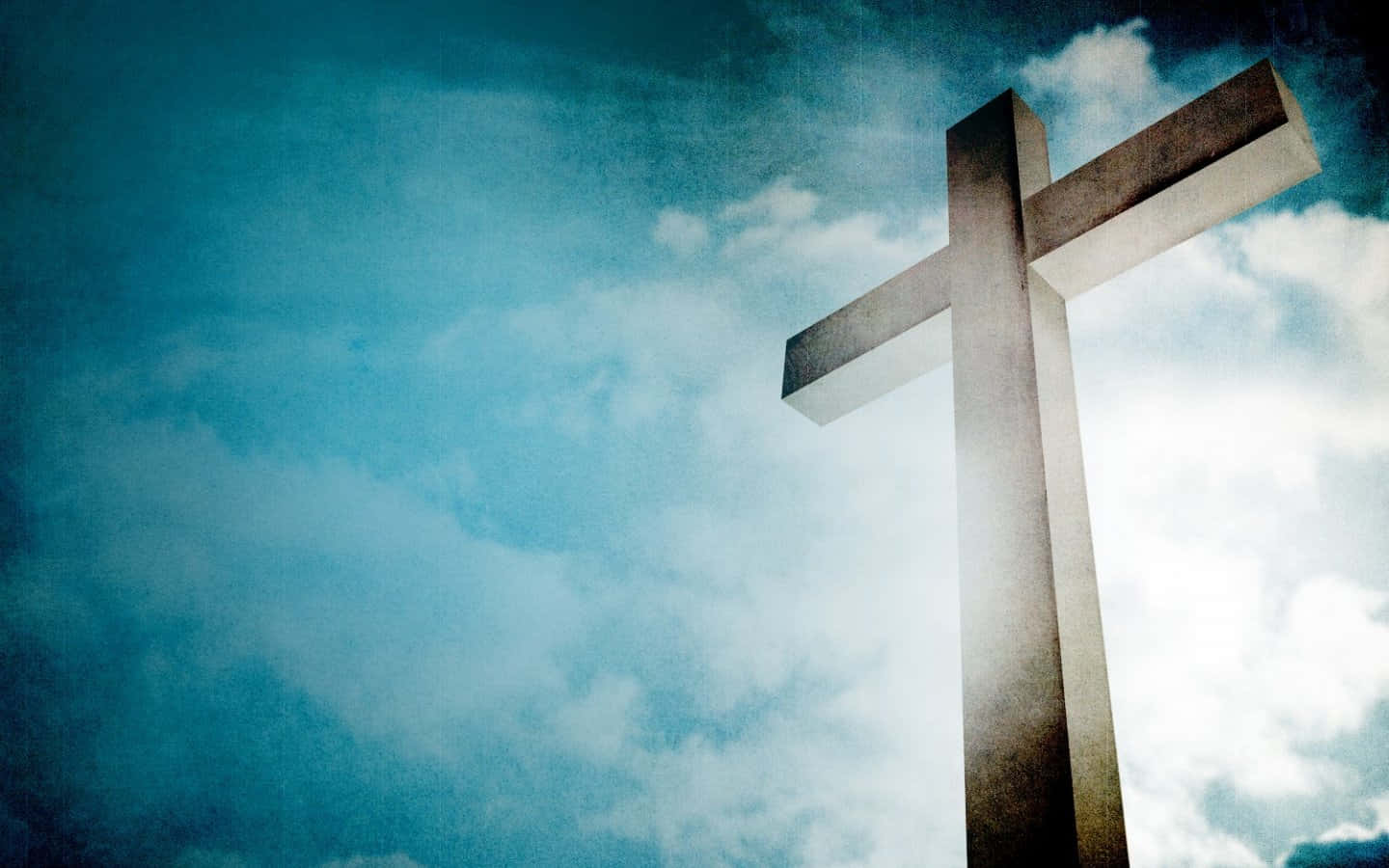 Cool Christian 桌布 壁紙 — 一個風化的石十字架高高聳立，映襯著充滿旋轉雲朵的戲劇性藍天。