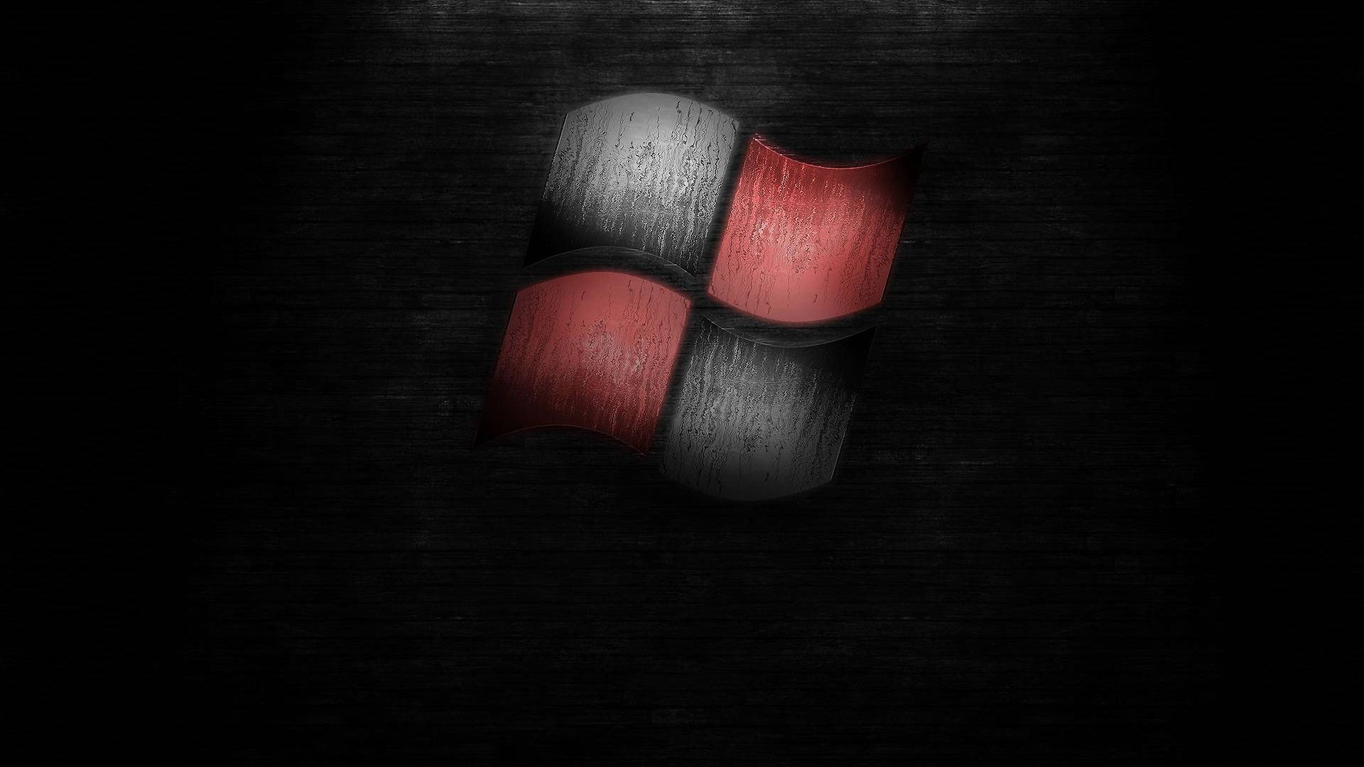 Dark Windows 桌布 壁紙 — 一個風化的紅色和灰色Windows標誌在深色紋理背景上微微發光。