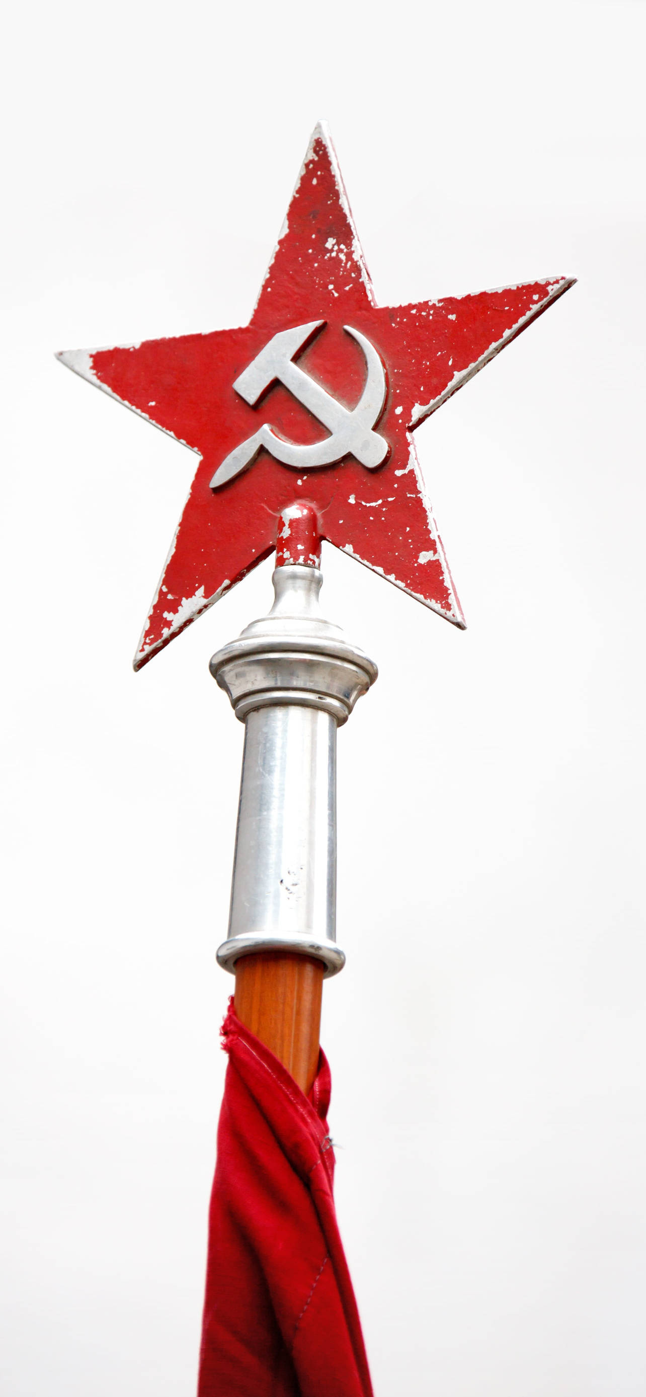 Red Star 桌布 壁紙 — 一個風化的紅色星星，頂部有鎚子和鐮刀標誌，位於旗桿上，背景為純白色。