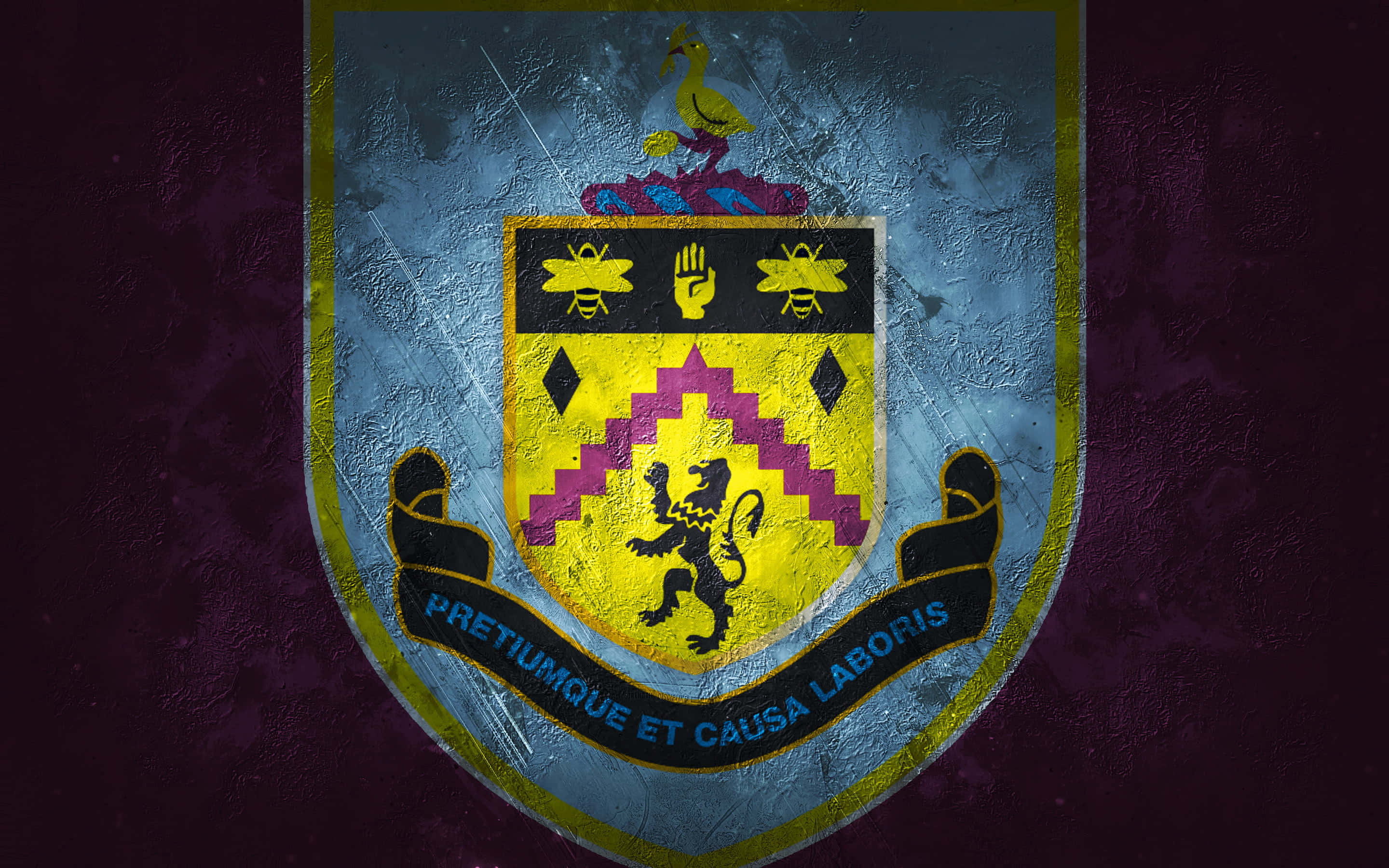 Burnley Fc 桌布 壁紙 — 一個風化的紋章盾牌，上面有躍立的獅子和拉丁文格言，背景是帶紋理的紫色和藍色。
