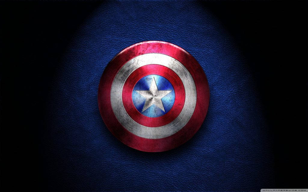 shield 桌布 壁紙 — 一個風化的美國隊長盾牌在聚光燈下，在深藍色紋理布料上發光。