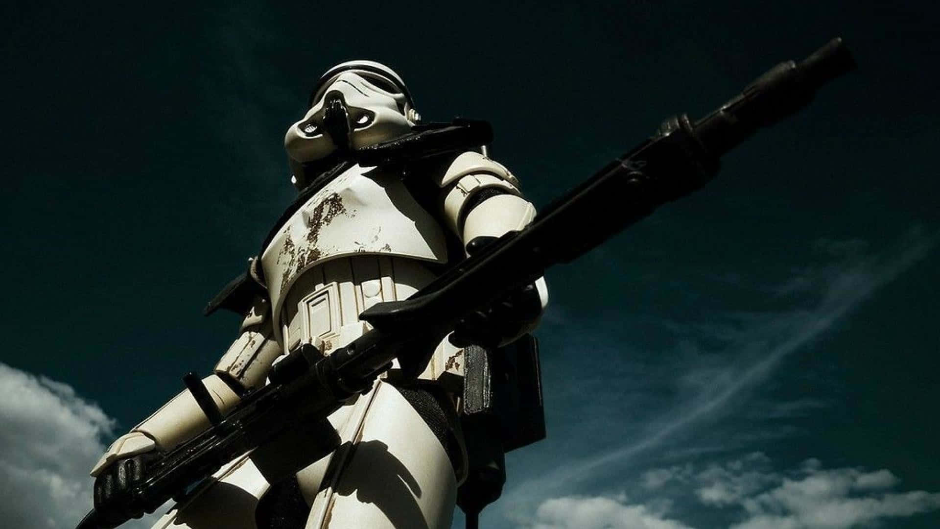 Galactic Empire 桌布 壁紙 — 一個風化的風暴兵高聳站立在戲劇性的多雲天空下，手持爆能步槍。