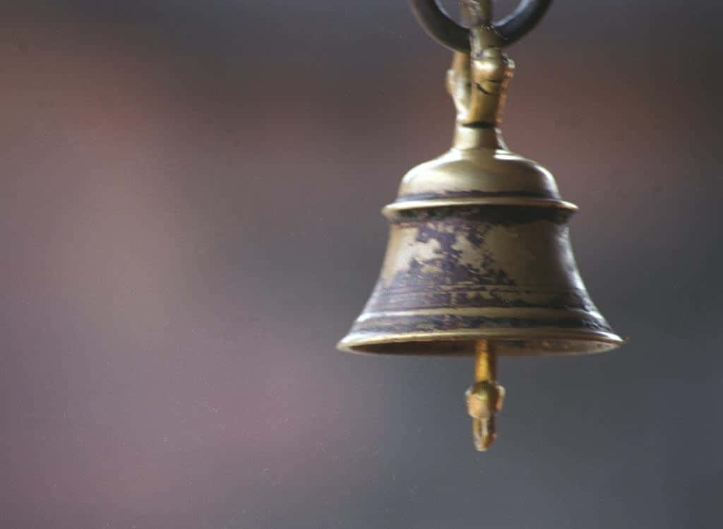 Bell 桌布 壁紙 — 一個風化的黃銅鐘懸掛在柔和漸變背景上，帶有溫暖柔和的色調。