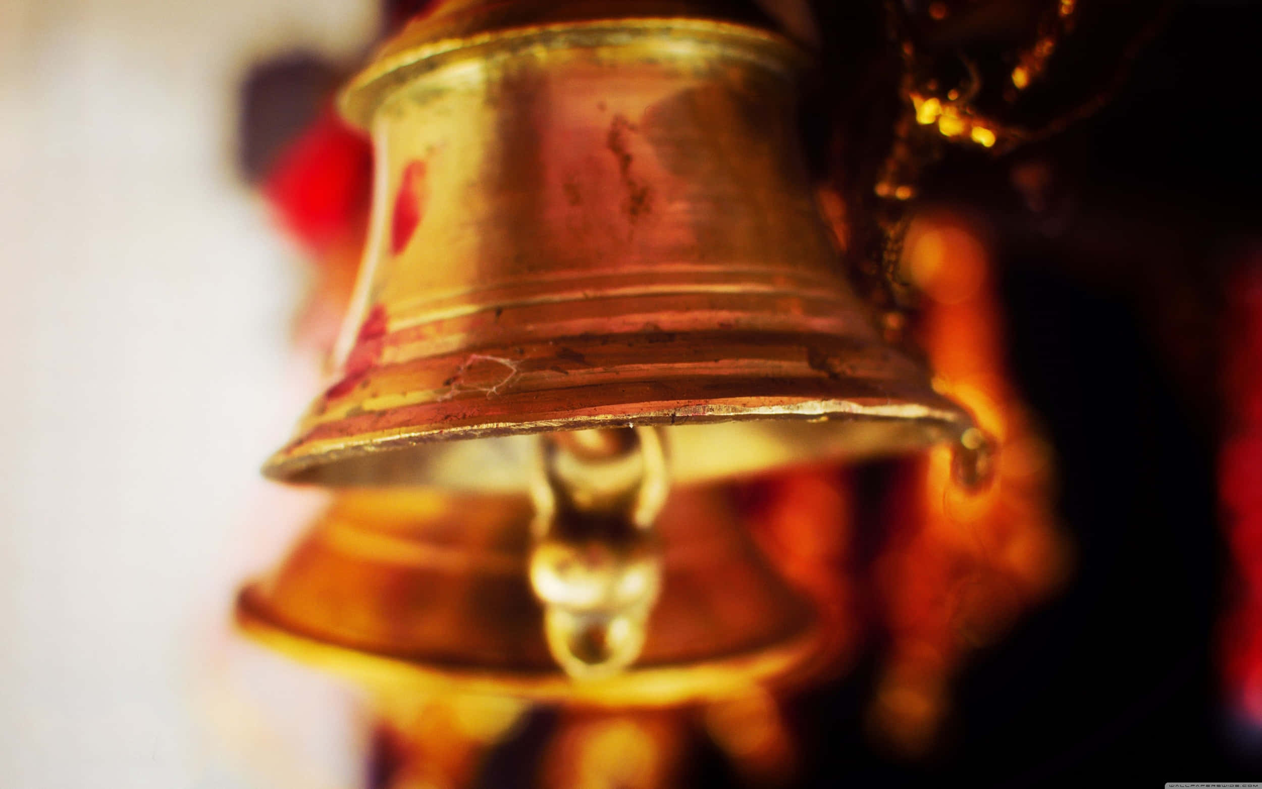 Bell 桌布 壁紙 — 一個風化黃銅鐘的特寫，溫暖的金色光線在其表面反射，背景模糊。