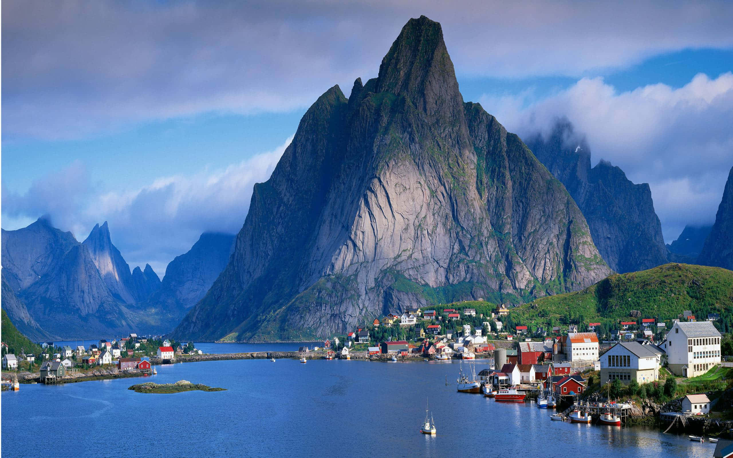 Steep 桌布 壁紙 — 一個風景如畫的海邊村莊，坐落在高聳崎嶇的山脈腳下，天空局部多雲。