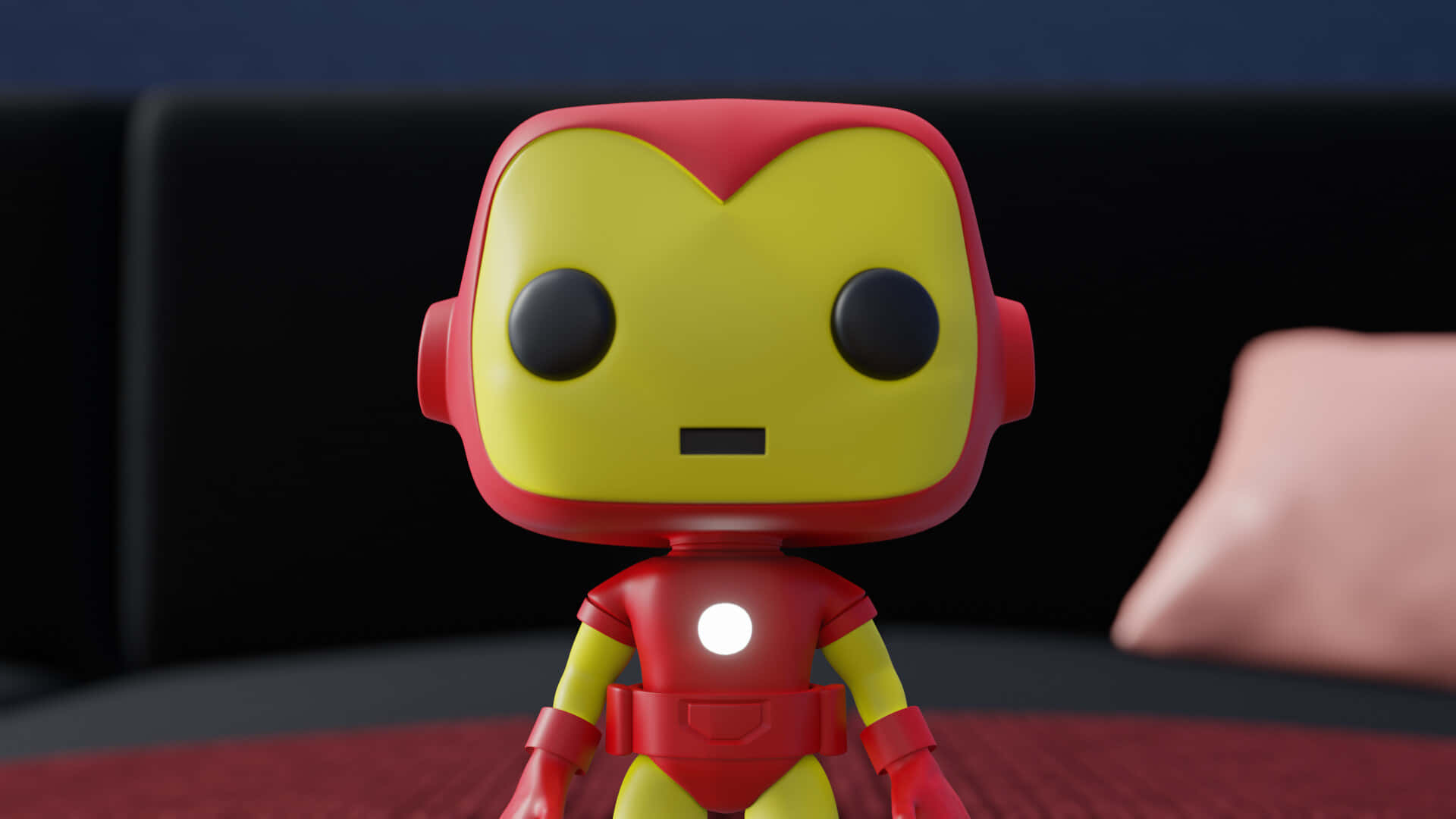 Iron Man Pop Figures 桌布 壁紙 — 一個風格化的 Iron Man Funko Pop 人偶站在紅色表面上，背景有黑色沙發和粉紅色枕頭。