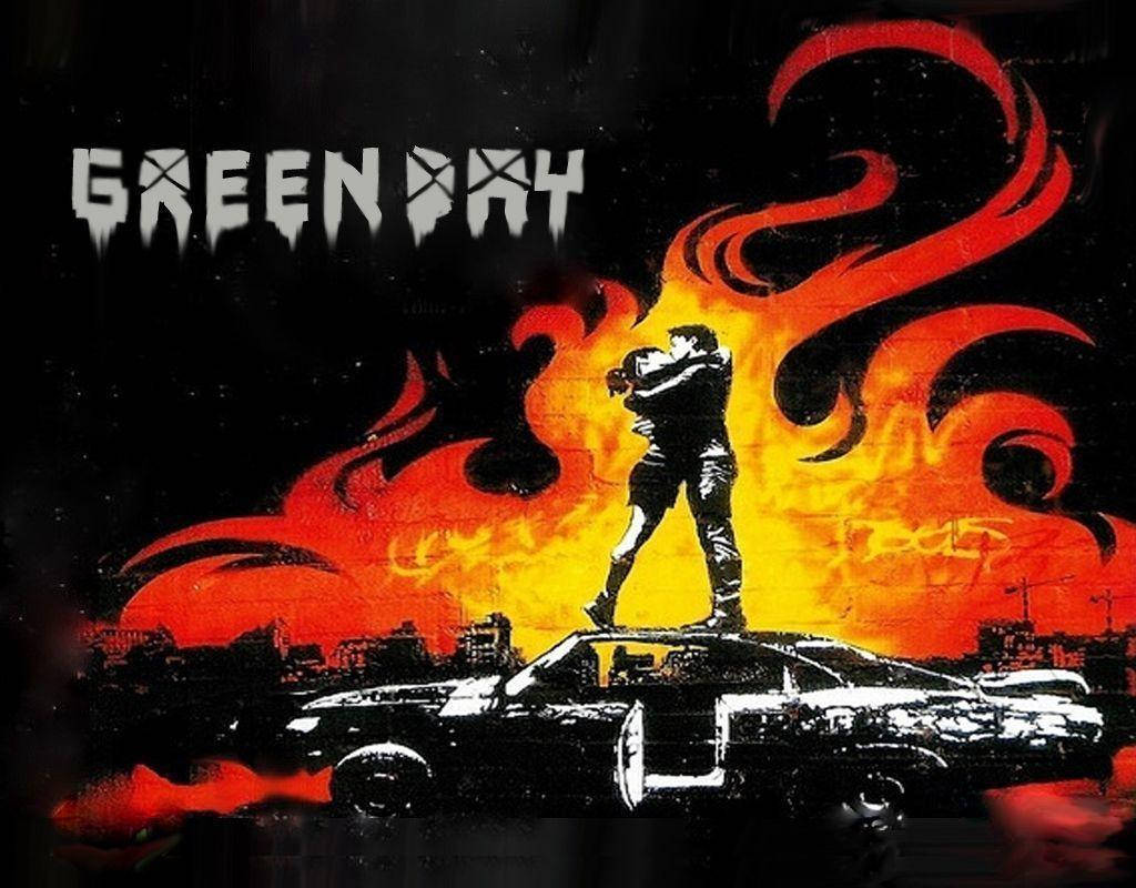 Green Day 桌布 壁紙 — 一個風格化的人物剪影站在車頂上，背景是熾熱的橙色和紅色爆炸，並帶有 'GREEN DAY' 文字。