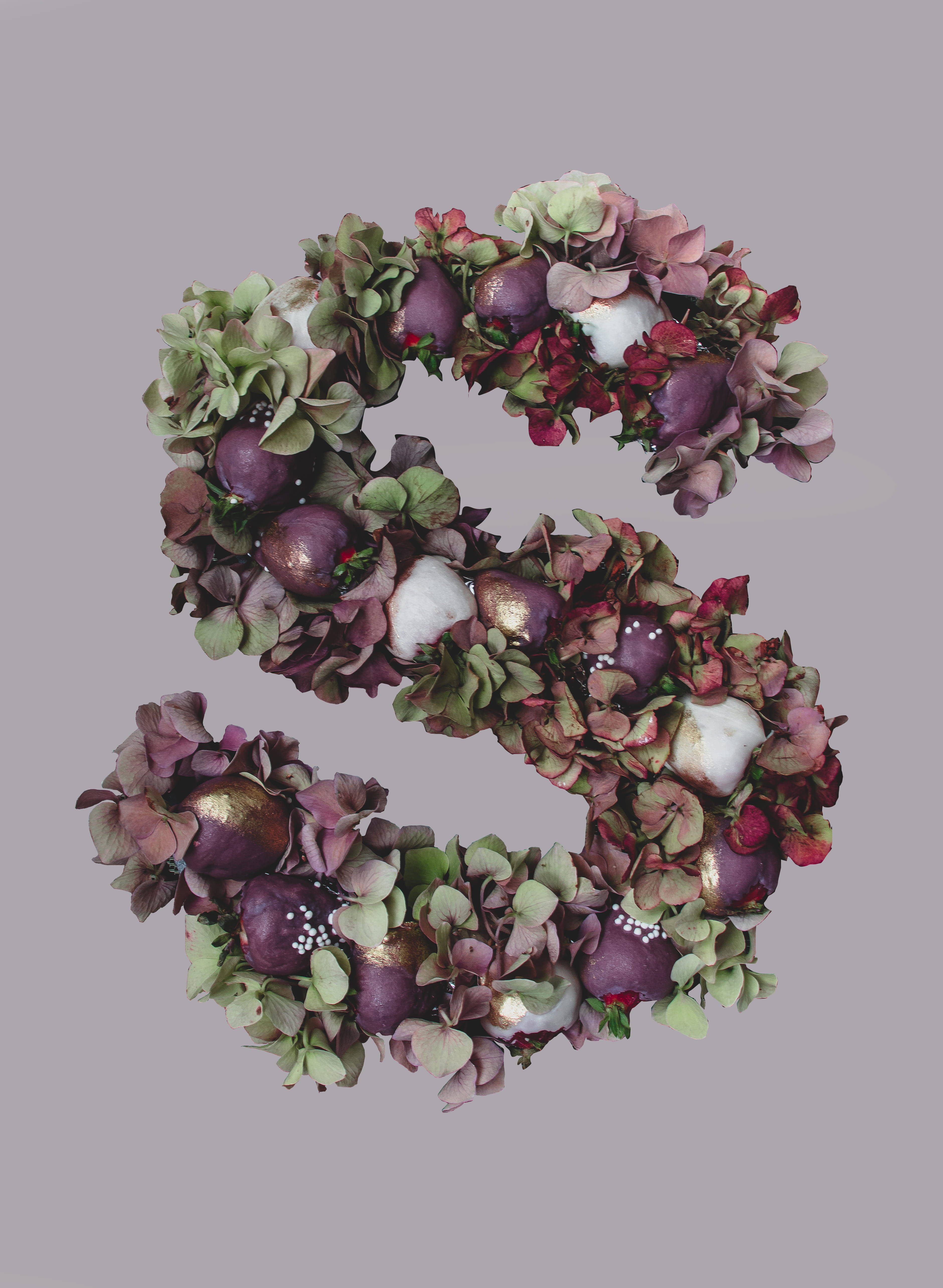 S Alphabet 桌布 壁紙 — 一個風格化的字母S，由茂盛的紫色和綠色繡球花組成，帶有白色點綴，背景為柔和的灰色。