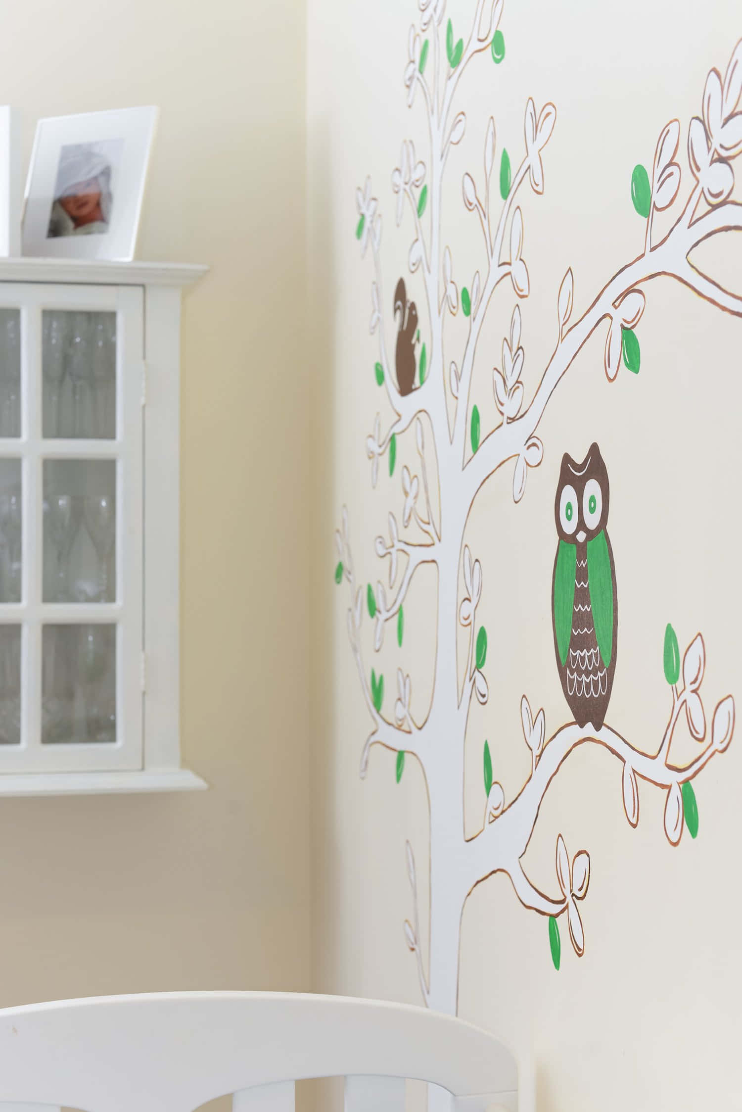 Wall Painting 桌布 壁紙 — 一個風格化的樹形牆貼，上面有綠色貓頭鷹棲息在樹枝上，裝飾在白色櫃子旁邊的奶油色牆壁上。