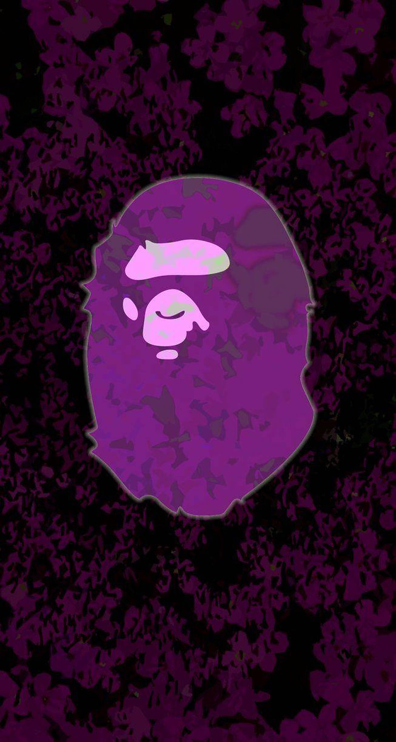 bape logo 桌布 壁紙 — 一個風格化的紫色猿頭，帶有發光的眼睛，置於有紋理的深紫色和黑色背景上。