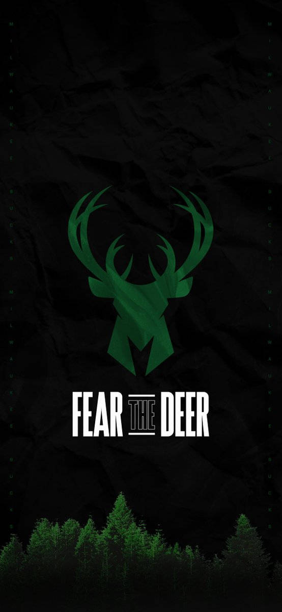 Bucks 桌布 壁紙 — 一個風格化的綠色鹿頭標誌，帶有文字 fear the deer，置於深色皺紋紋理上，底部有森林剪影。