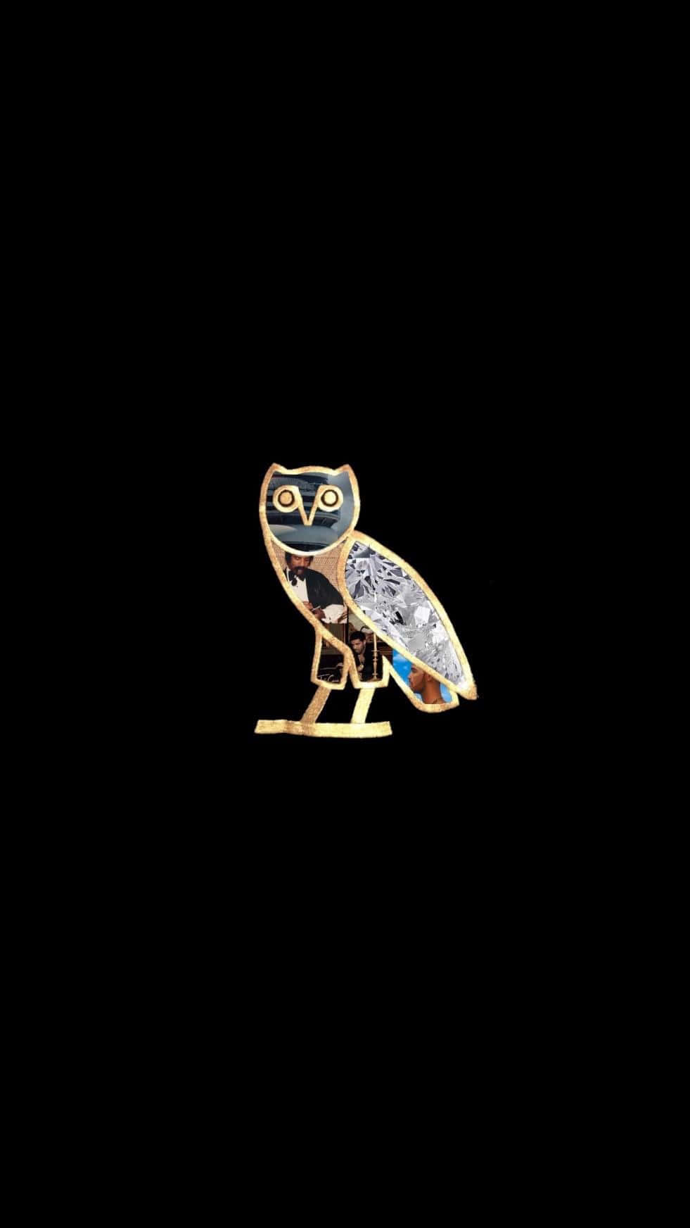 Drake Ovo Owl iPhone 桌布 壁紙 — 一個風格化的金色貓頭鷹別針，帶有精緻的銀色和藍色琺瑯細節，位於純黑色背景中央。