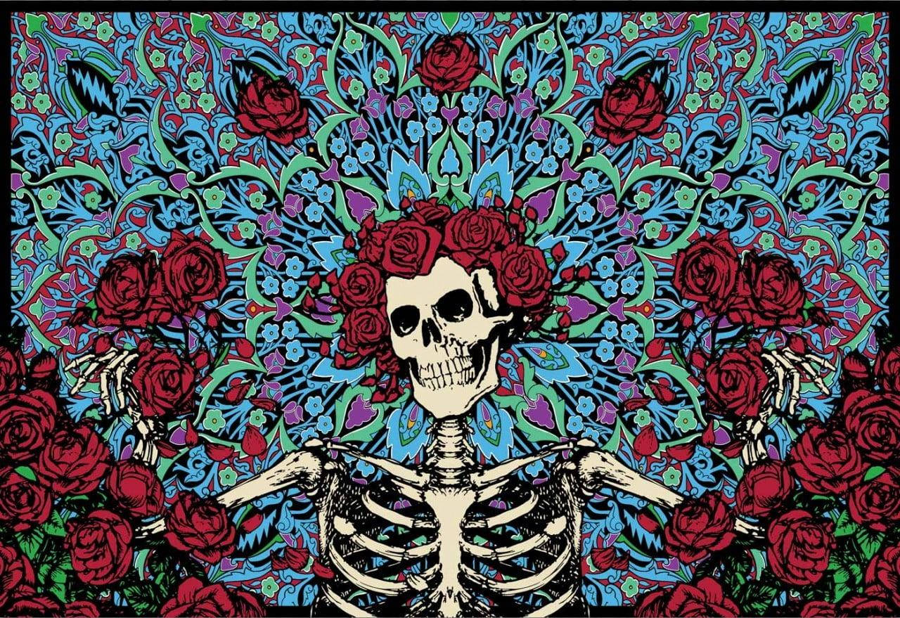 Dia De Los Muertos 桌布 壁紙 — 一個風格化的骷髏裝飾著紅玫瑰，從藍色、綠色和紫色的鮮豔花卉圖案中浮現。