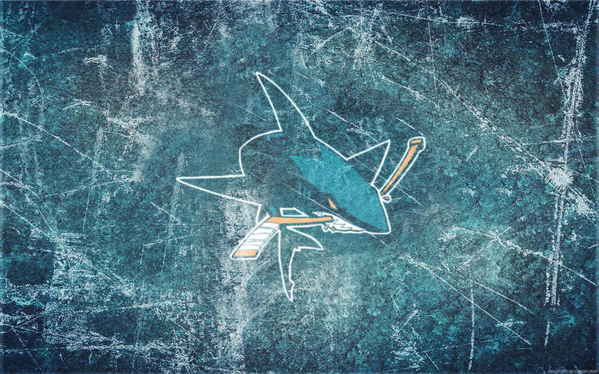 sharks 桌布 壁紙 — 一個風格化的鯊魚標誌，配以曲棍球棒和冰球，在帶有刮痕的藍綠色冰面場地上滑行。