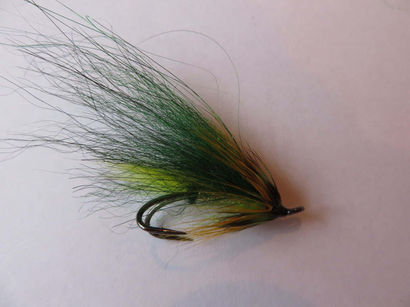 Fishing Bait 桌布 壁紙 — 一個飛蠅釣魚假餌的特寫，綠色和黃色的纖維在純白色背景上展開。