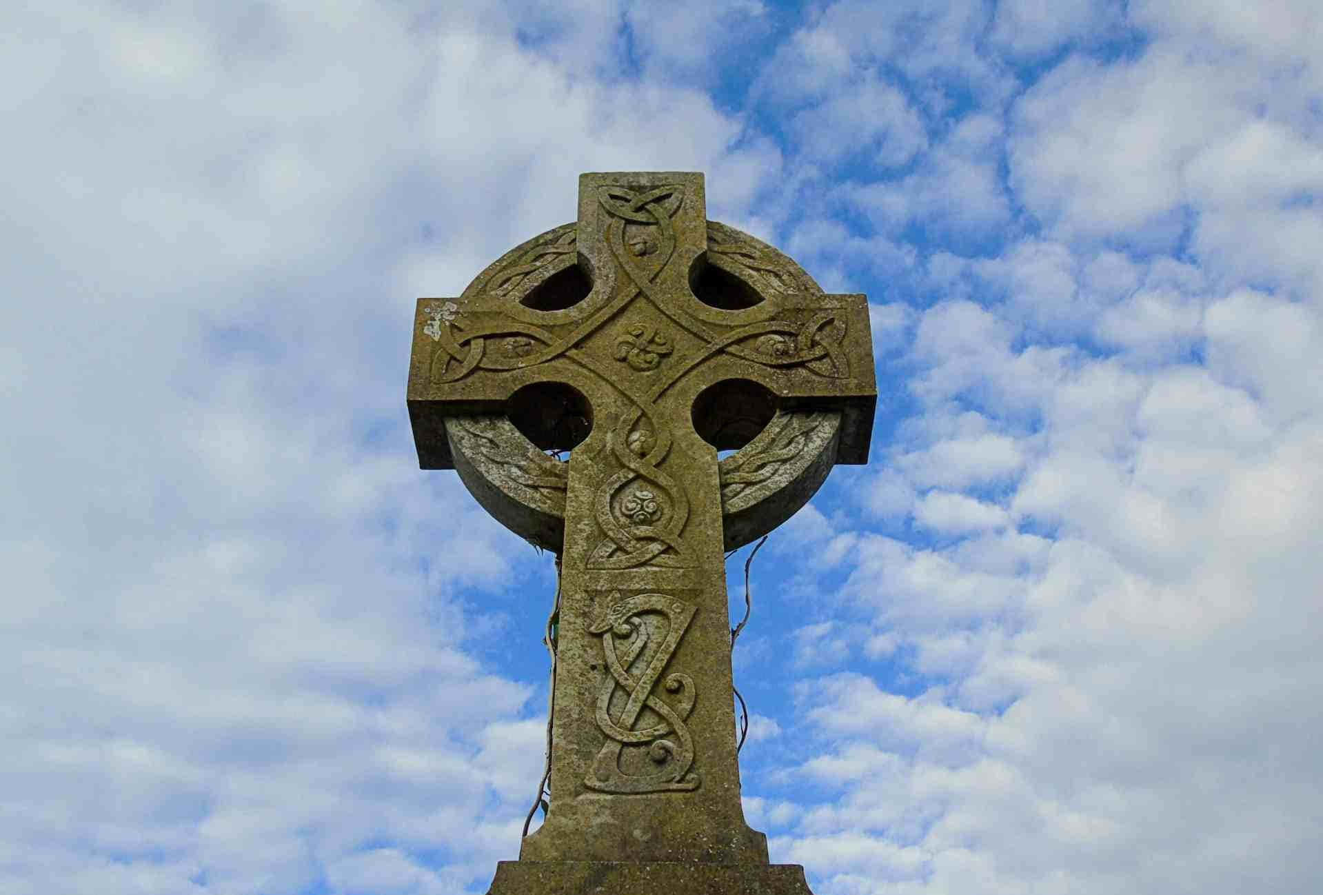 Celtic Irish 桌布 壁紙 — 一個飽經風霜的凱爾特十字架，在點綴著蓬鬆白雲的明亮藍天下高高聳立。