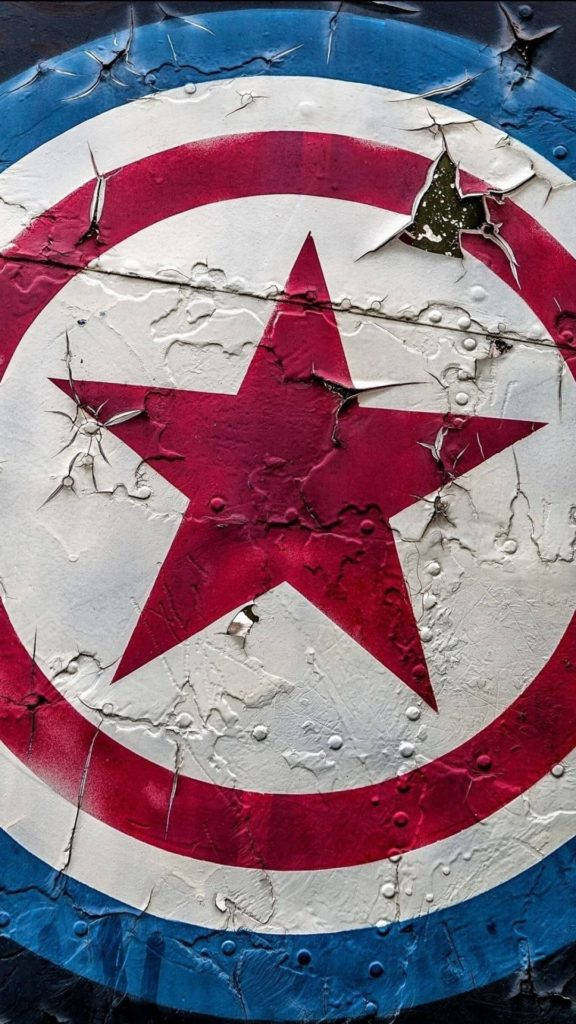 Captain America iPhone 桌布 壁紙 — 一個飽經風霜的美國隊長盾牌，帶有裂紋的油漆和生鏽的鉚釘，在深色背景上顯示戰鬥傷痕。
