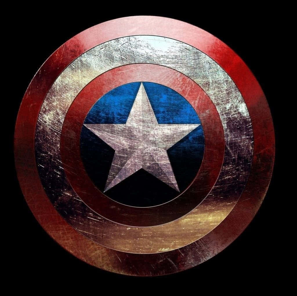 Captain America Logo 桌布 壁紙 — 一個飽經風霜的美國隊長盾牌，帶有紅、白、藍三色同心圓環，中央有一顆星，背景為黑色。