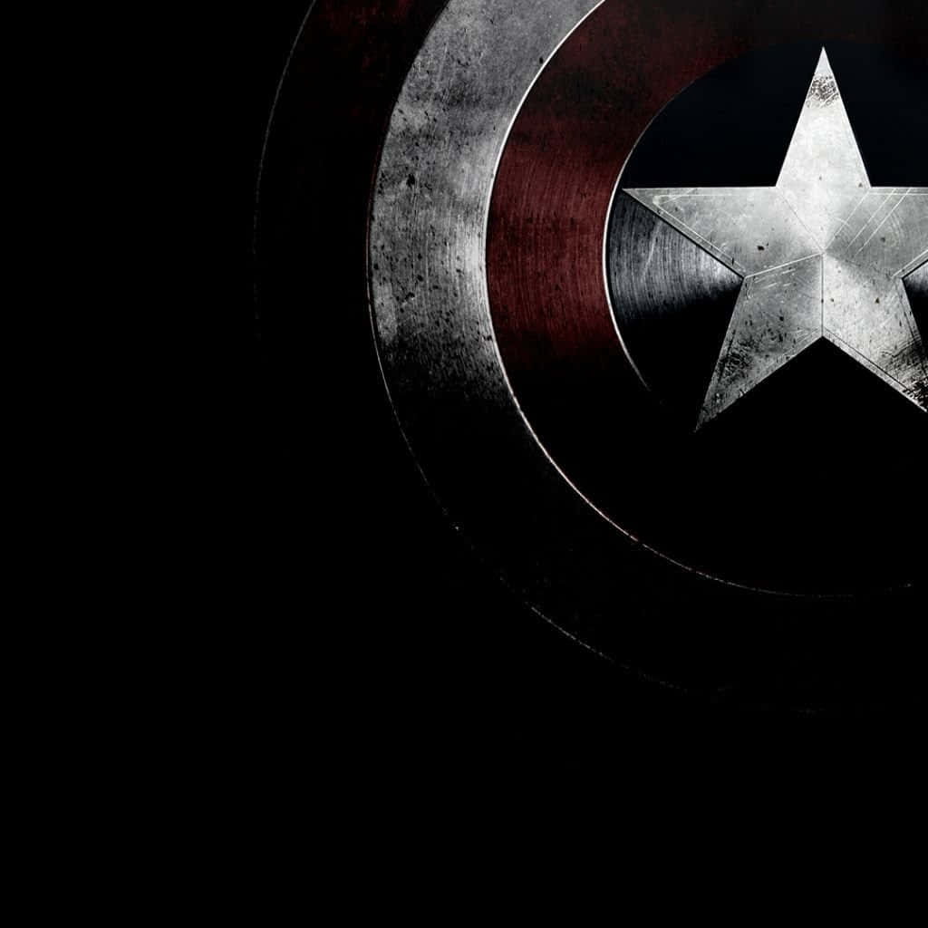 Captain America Logo 桌布 壁紙 — 一個飽經風霜的美國隊長盾牌，帶有金屬星星和紅色條紋，在純黑背景上發光。