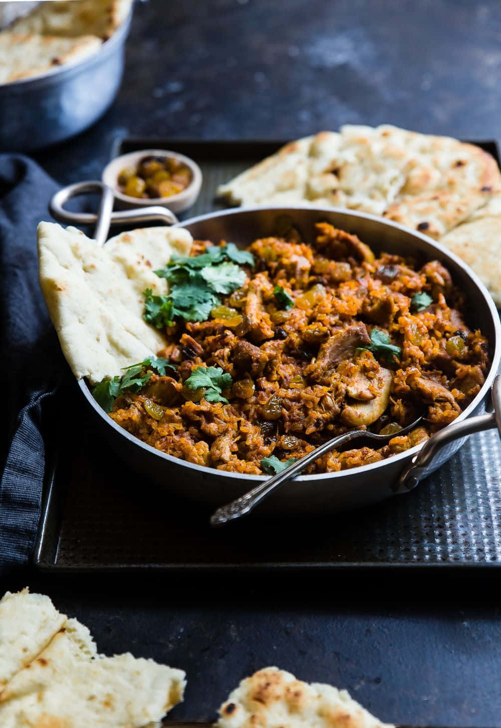 Curry 桌布 壁紙 — 一個香料豐富的咖哩，配有嫩肉和蘑菇，盛在金屬鍋中，配上溫熱的印度烤餅，並以新鮮香菜點綴。