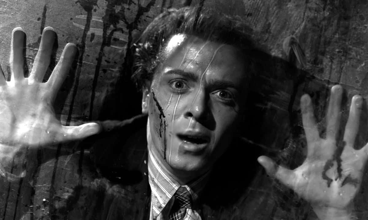 Film Noir 桌布 壁紙 — 一個驚恐的男人將雙手按在骯髒的玻璃窗上，黑色條紋順著他的臉流下，形成鮮明的黑白場景。