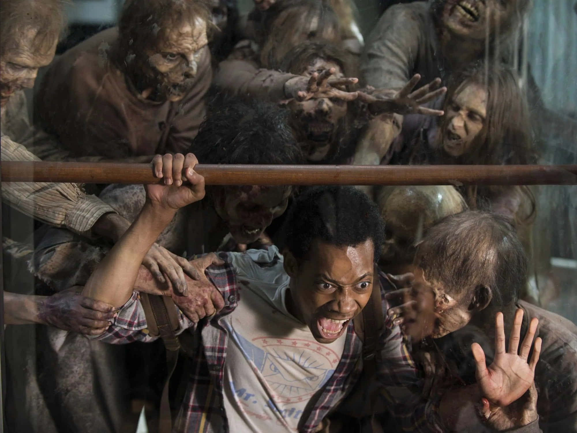 zombies 桌布 壁紙 — 一個驚恐的男人尖叫，被怪異的殭屍包圍，抓著一道屏障。